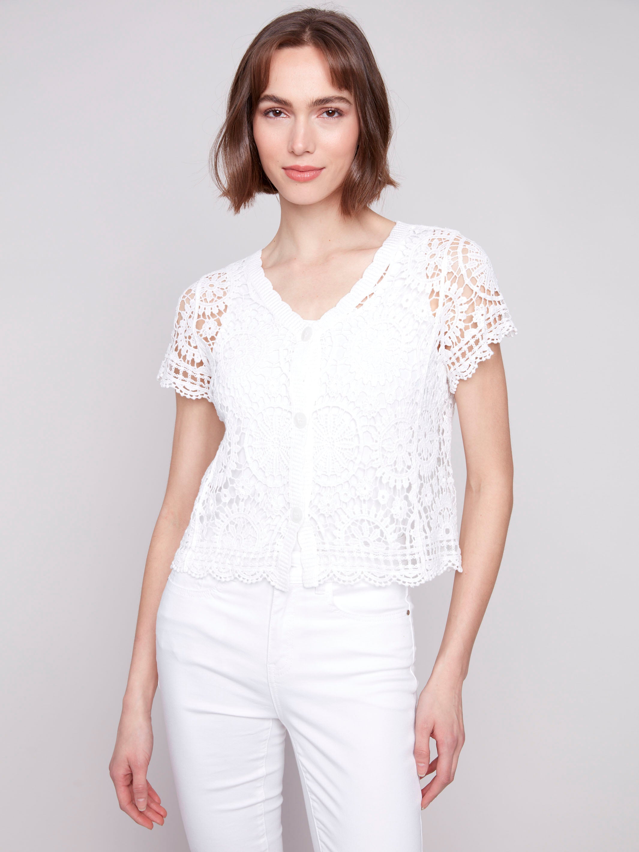 White cardigan with a V-neck and elegant crochet design by Charlie B.