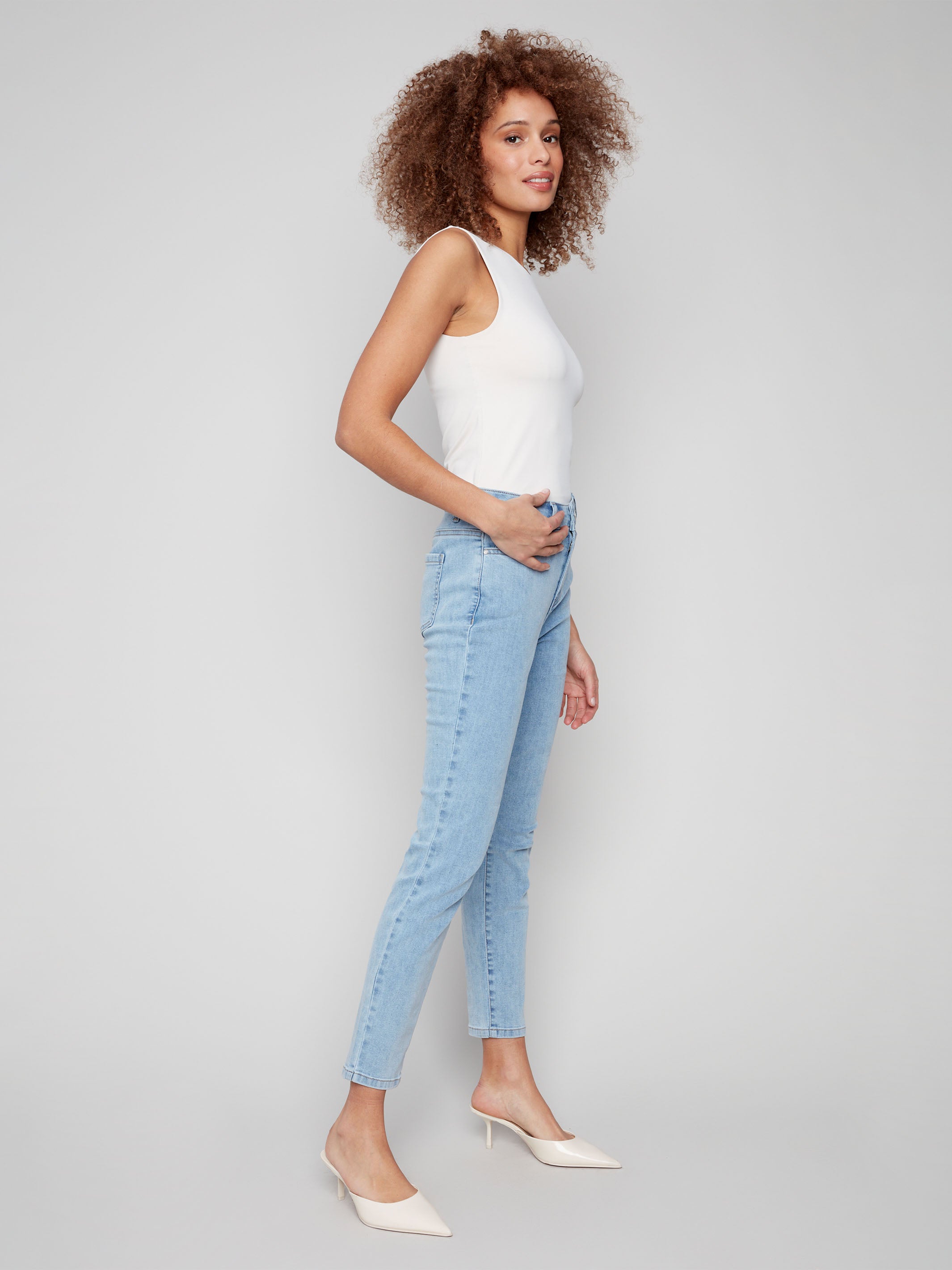 Light blue slim leg jeans with five-pocket design and button closure by Charlie B.