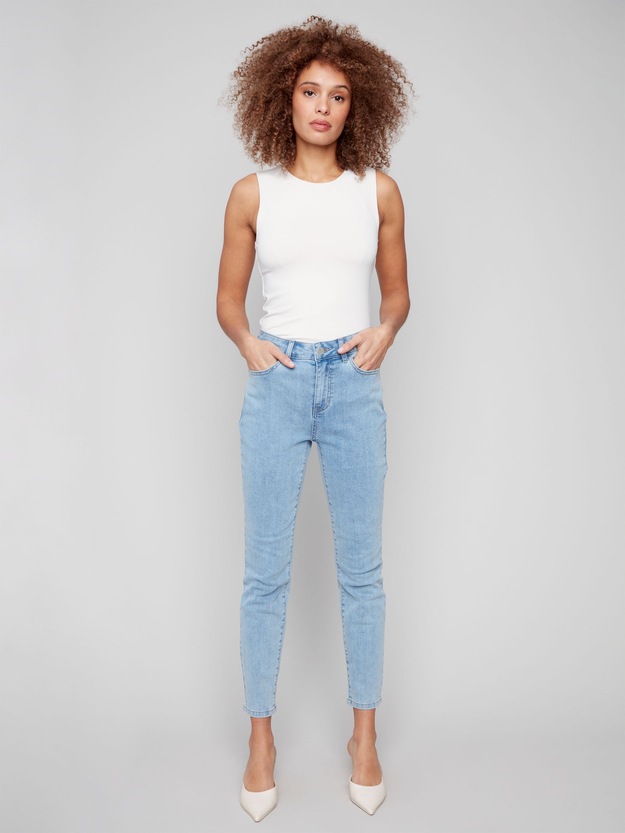 Light blue slim leg jeans with five-pocket design and button closure by Charlie B.