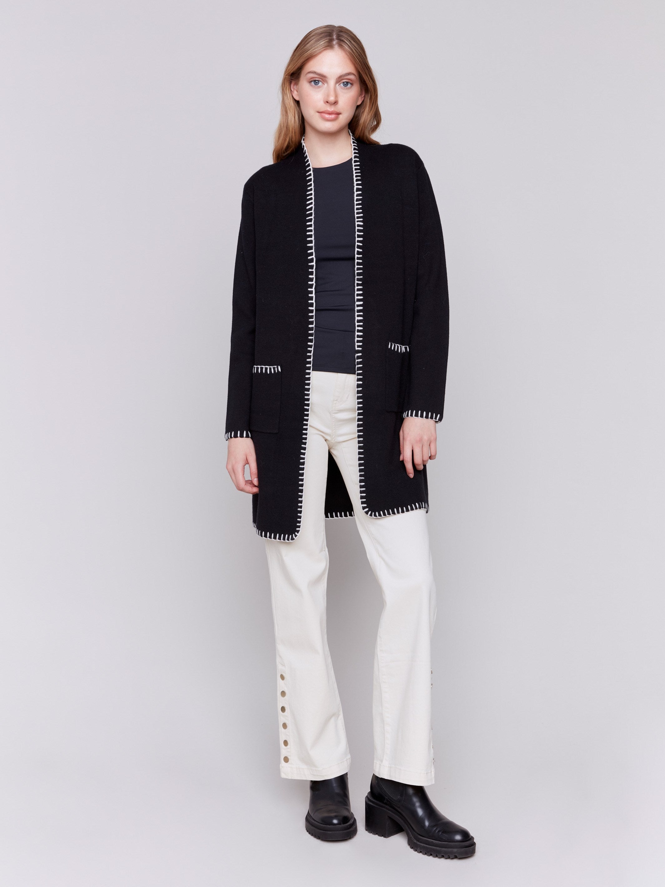 Black long cardigan with white blanket stitch trim, featuring patch pockets and an open front by Charlie B.