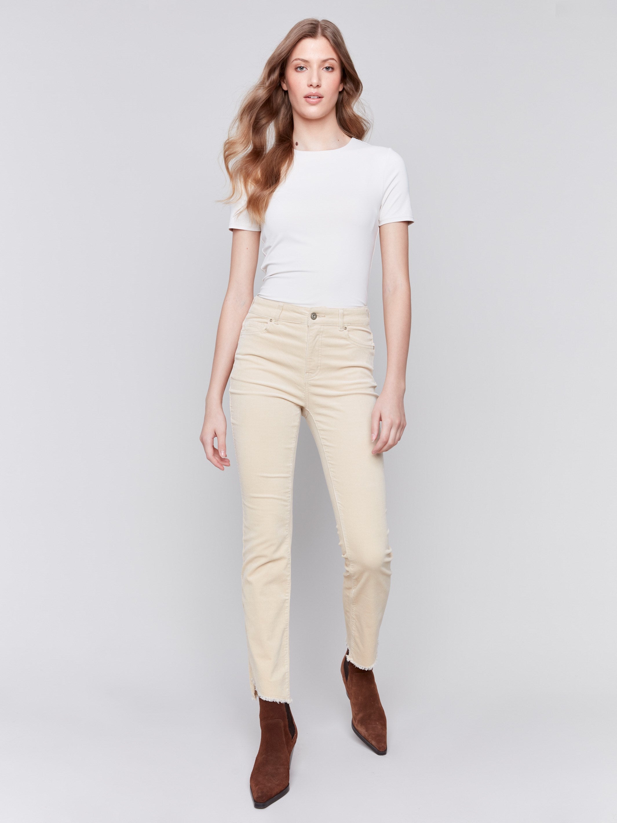 Natural-colored bootcut corduroy pants with an asymmetrical frayed hem and a bootcut fit by Charlie B.