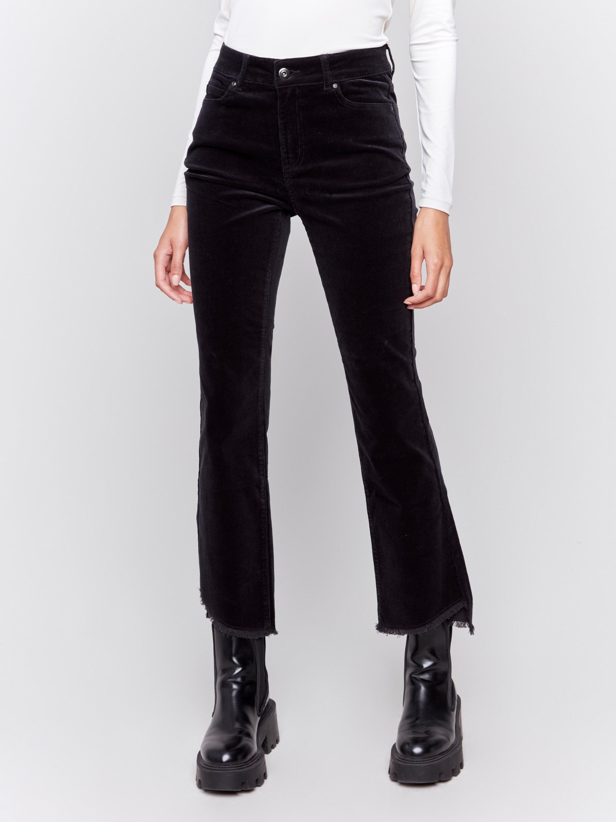 Black bootcut corduroy pants with an asymmetrical frayed hem and a bootcut fit by Charlie B.