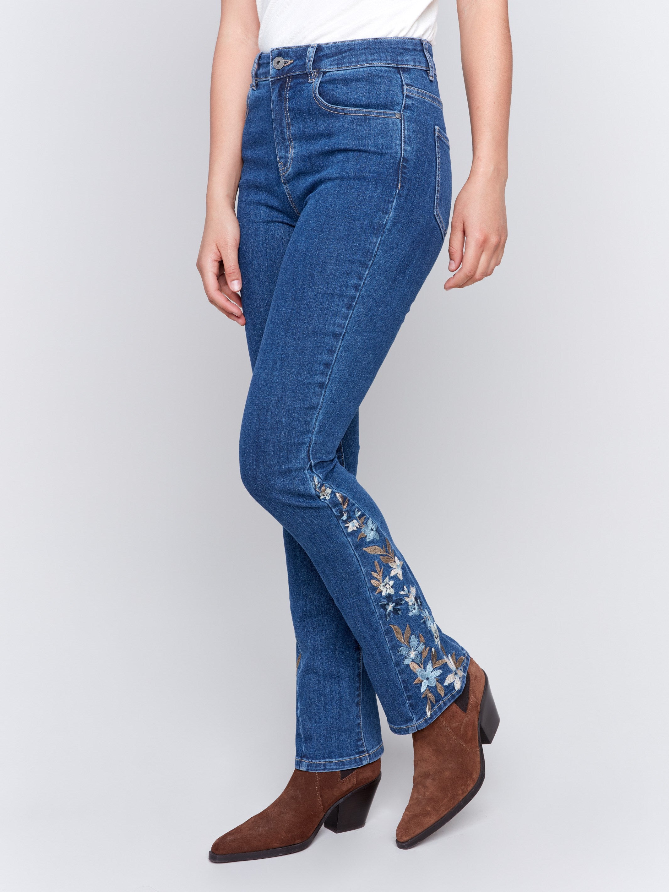 Indigo blue bootcut jeans with vibrant floral embroidery on the sides and a classic five-pocket design by Charlie B.