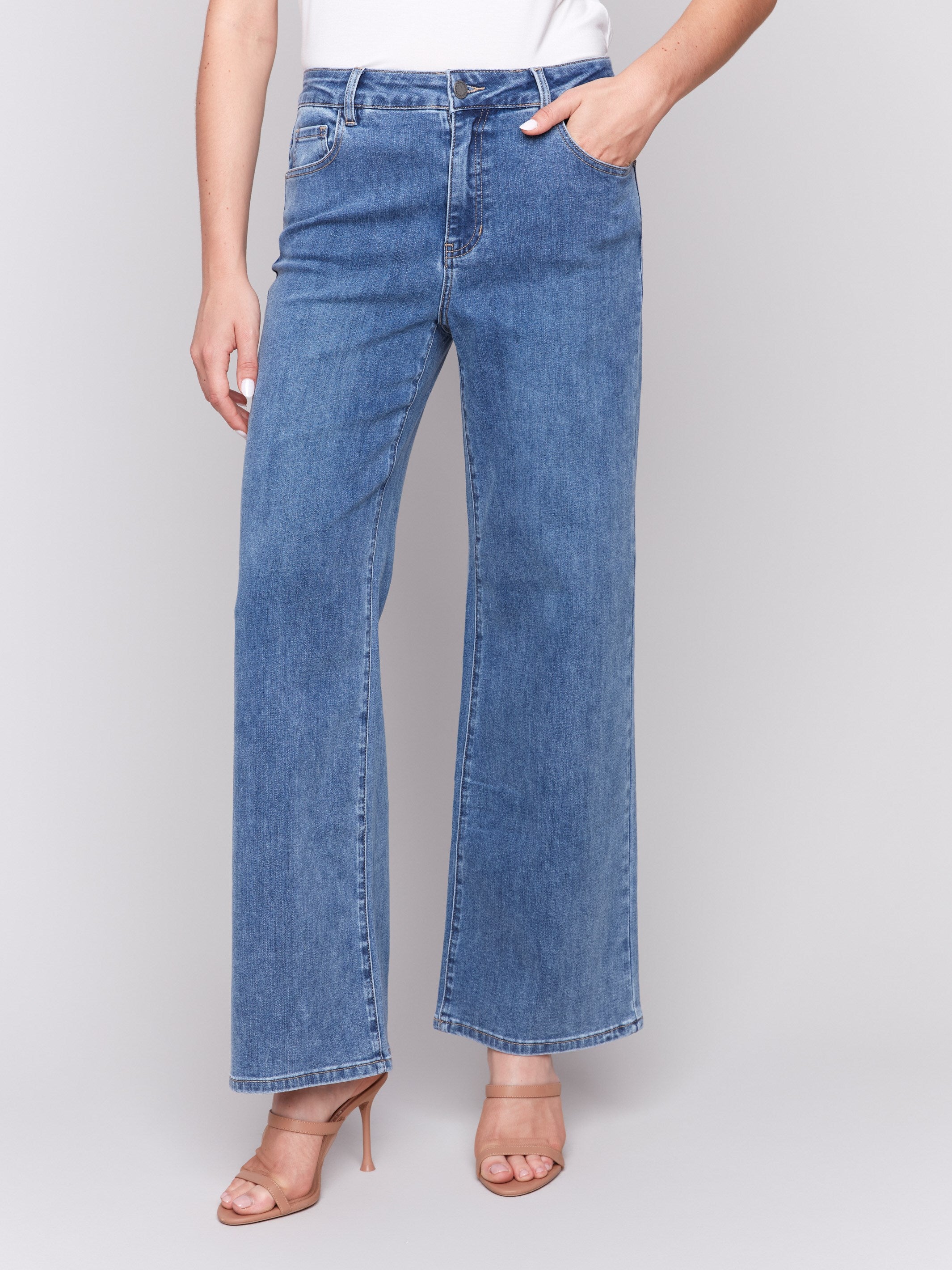 Medium blue wide-leg jeans with five-pocket design featuring a button closure and relaxed fit by Charlie B.