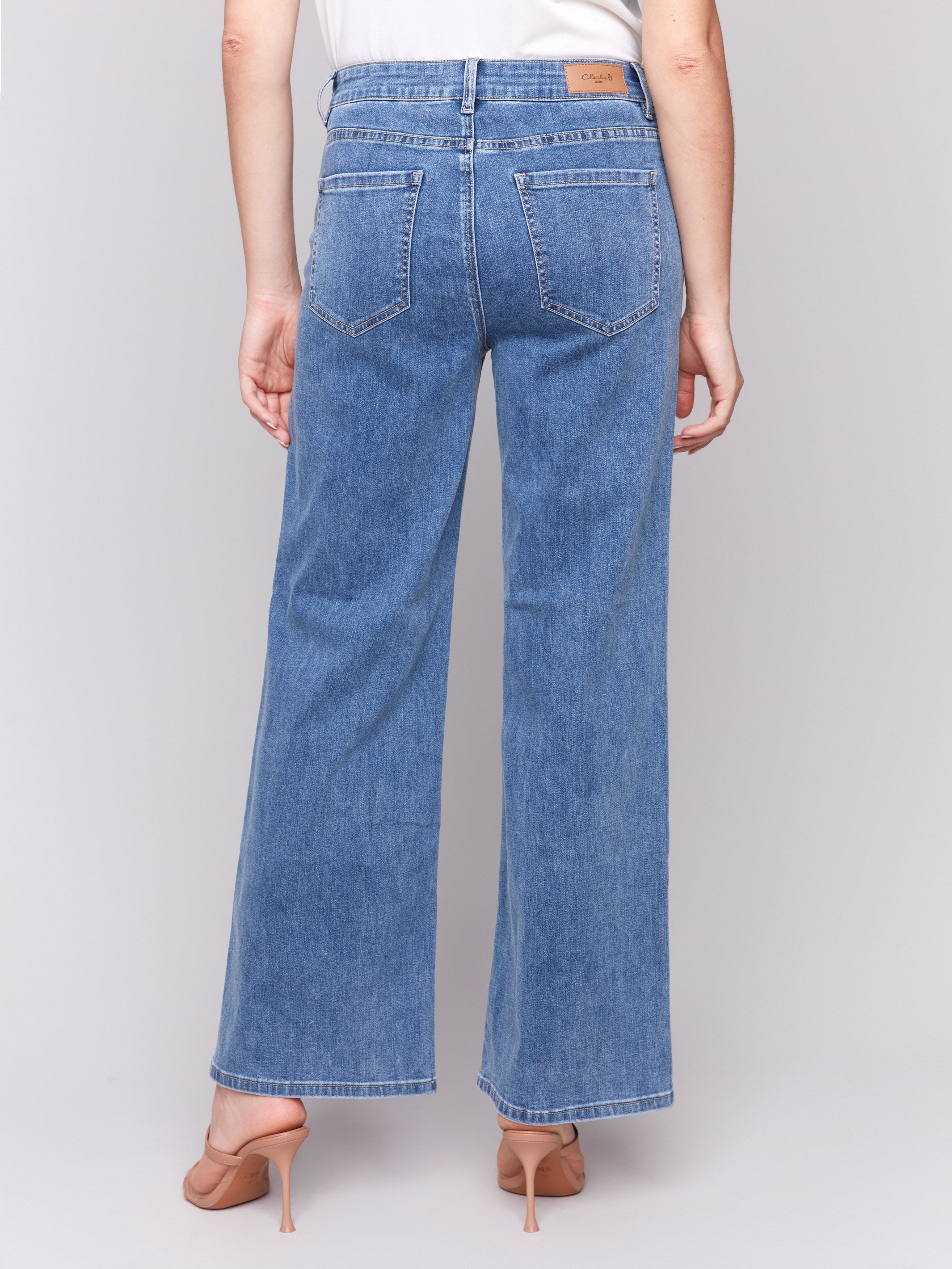 Medium blue wide-leg jeans with five-pocket design featuring a button closure and relaxed fit by Charlie B.