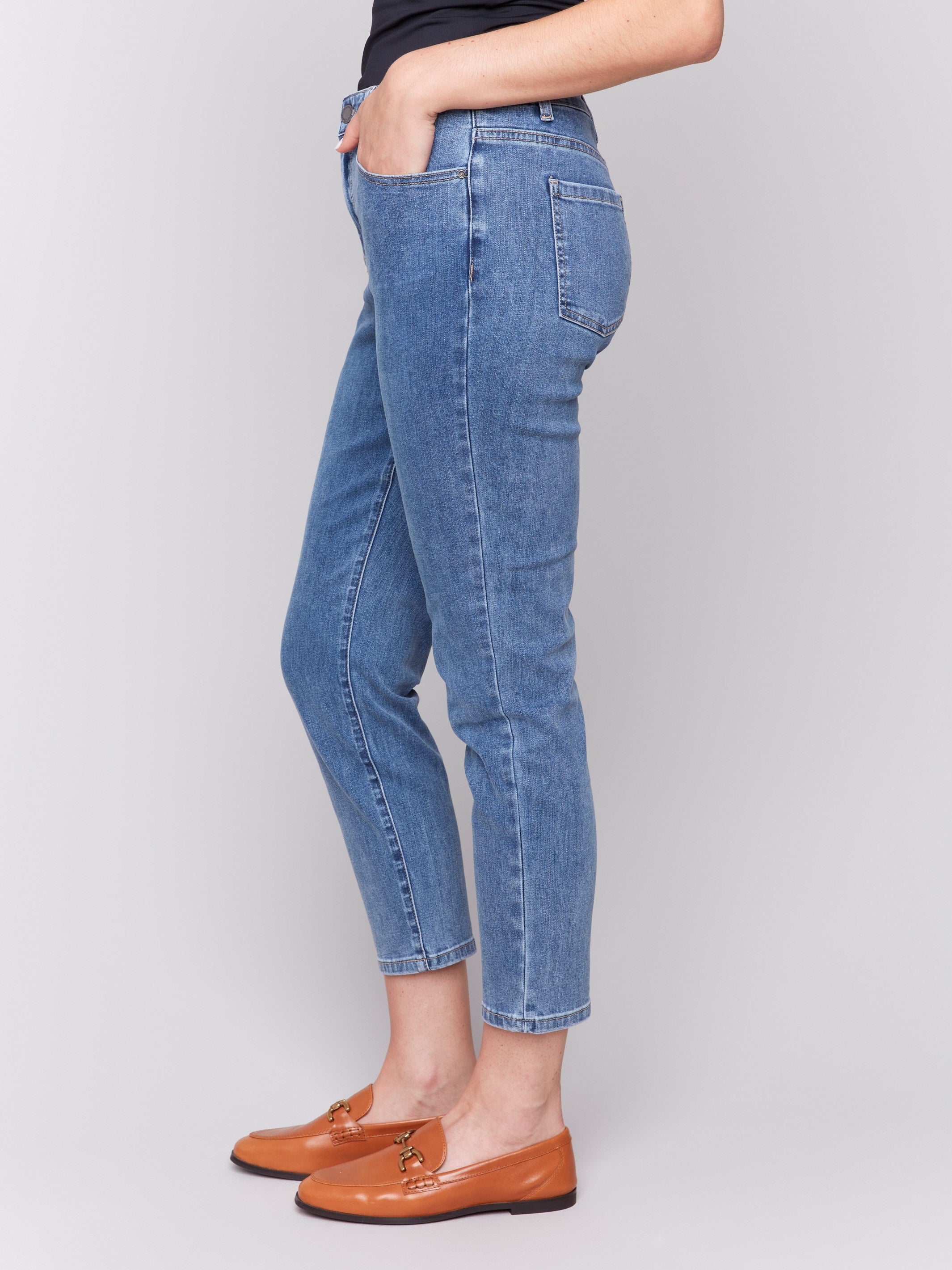 Medium blue slim leg jeans with five-pocket design and button closure by Charlie B.