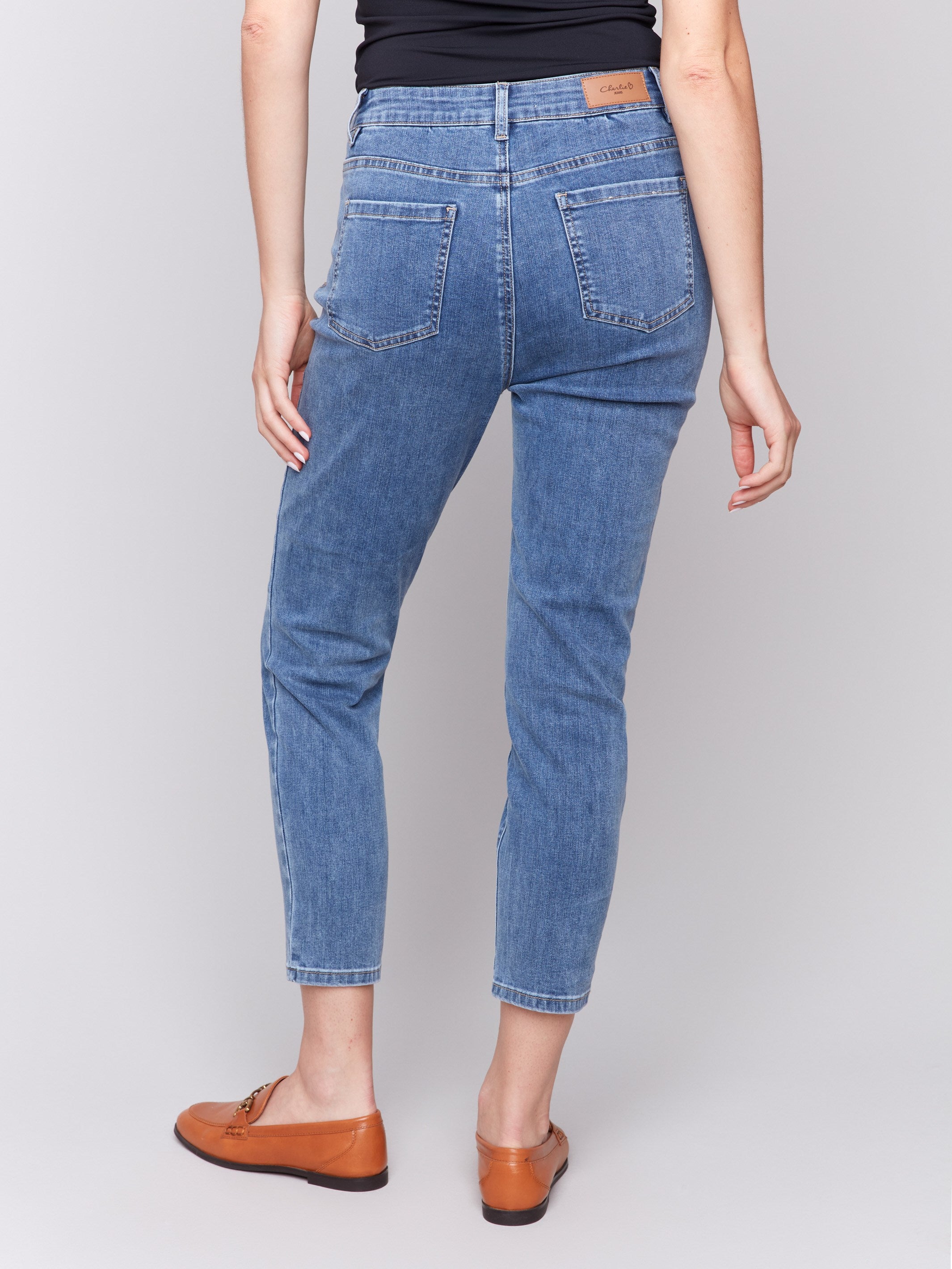 Medium blue slim leg jeans with five-pocket design and button closure by Charlie B.