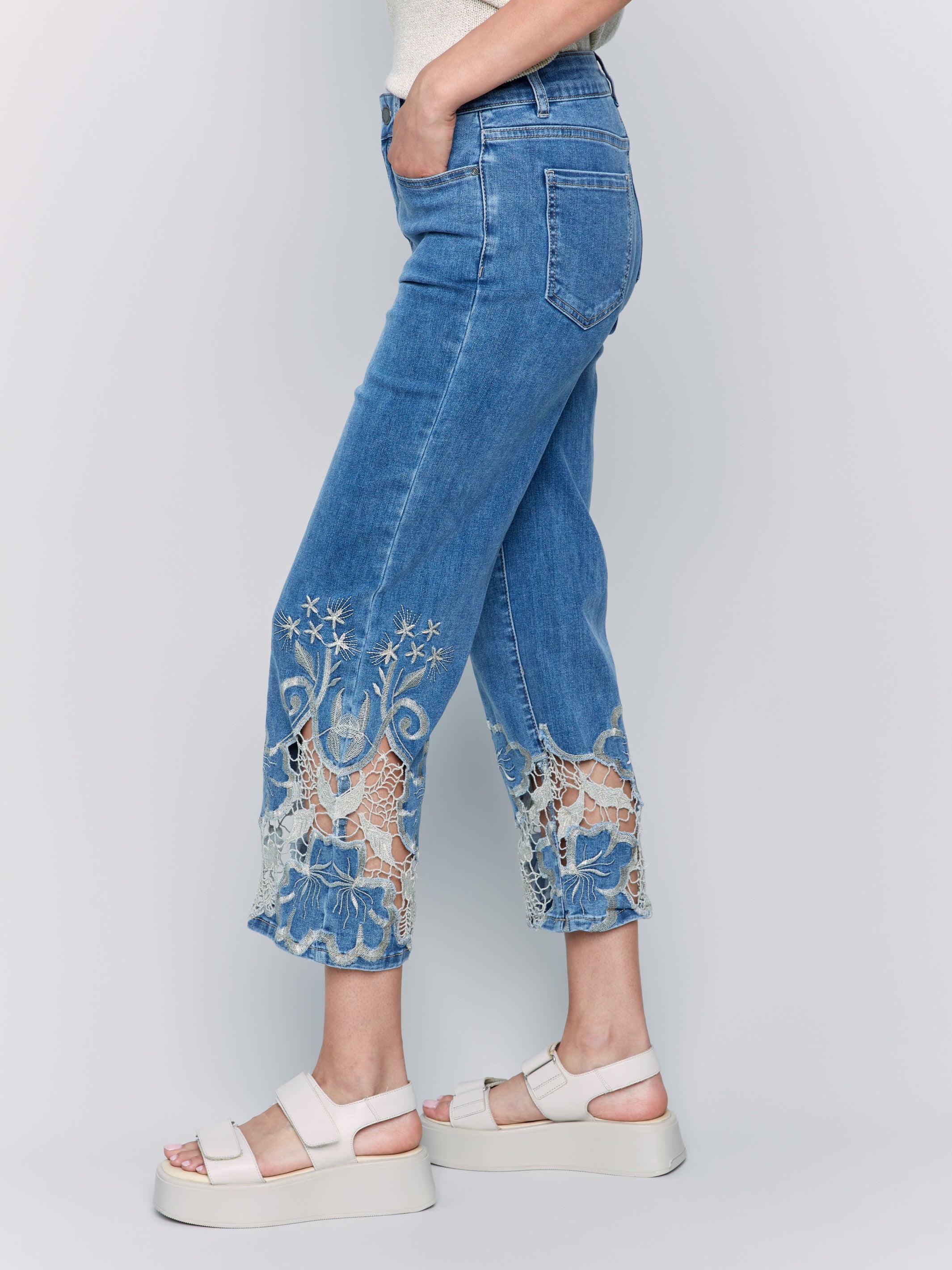 Flare leg medium blue jeans adorned with laser cut lace detail at hem by Charlie B.