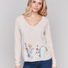 Beige cotton sweater featuring a V-neck design with intricate floral accents by Charlie B.