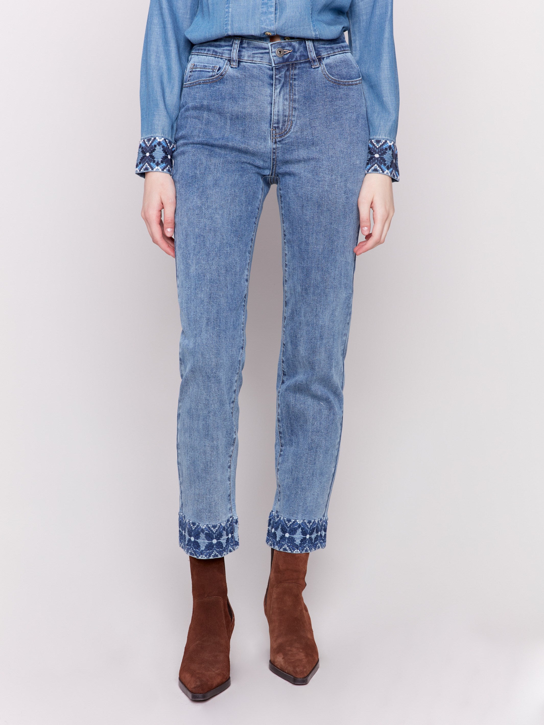 Medium blue straight leg jeans with intricate embroidered cuffs and a classic five-pocket design by Charlie B.