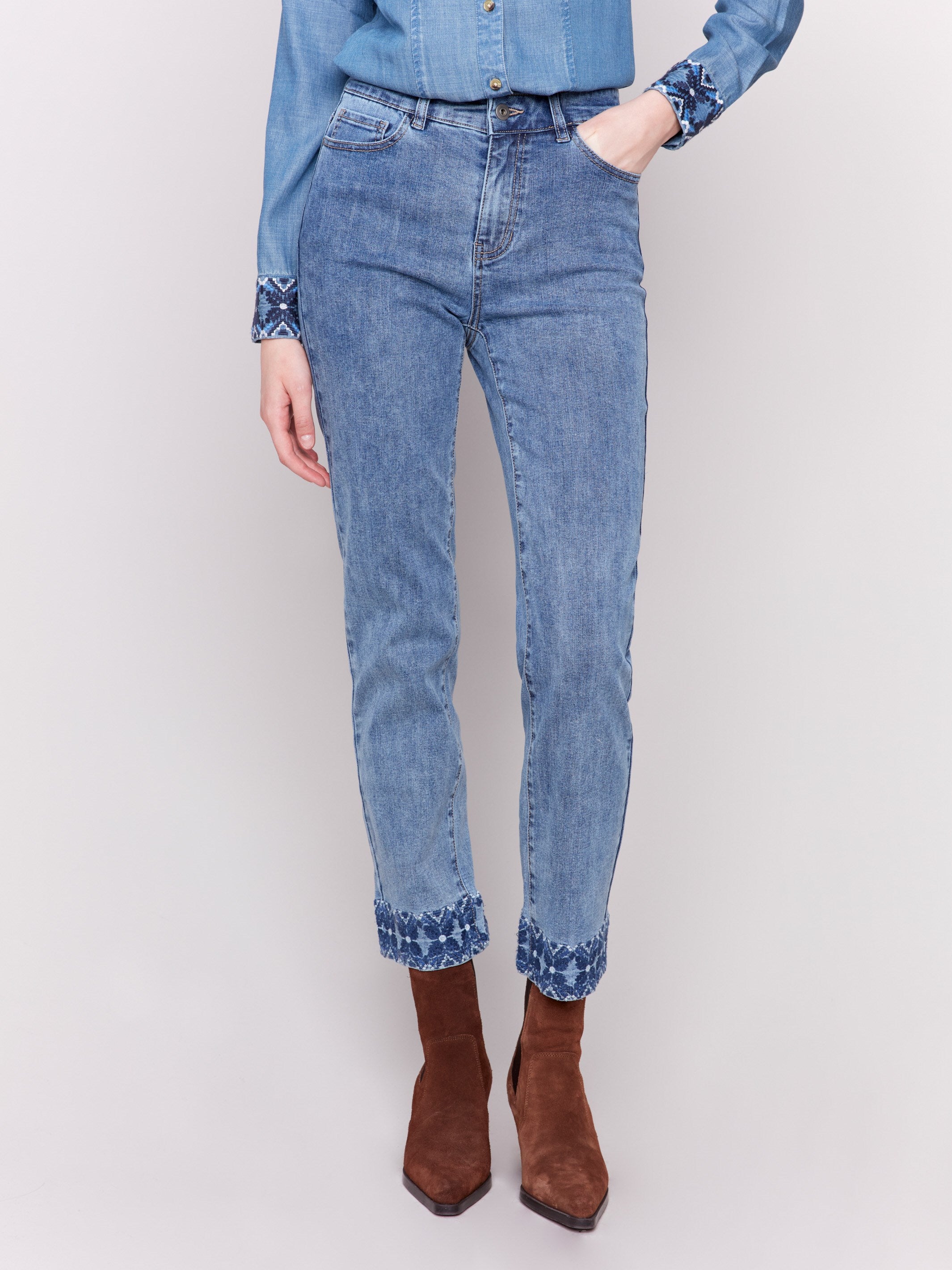 Medium blue straight leg jeans with intricate embroidered cuffs and a classic five-pocket design by Charlie B.