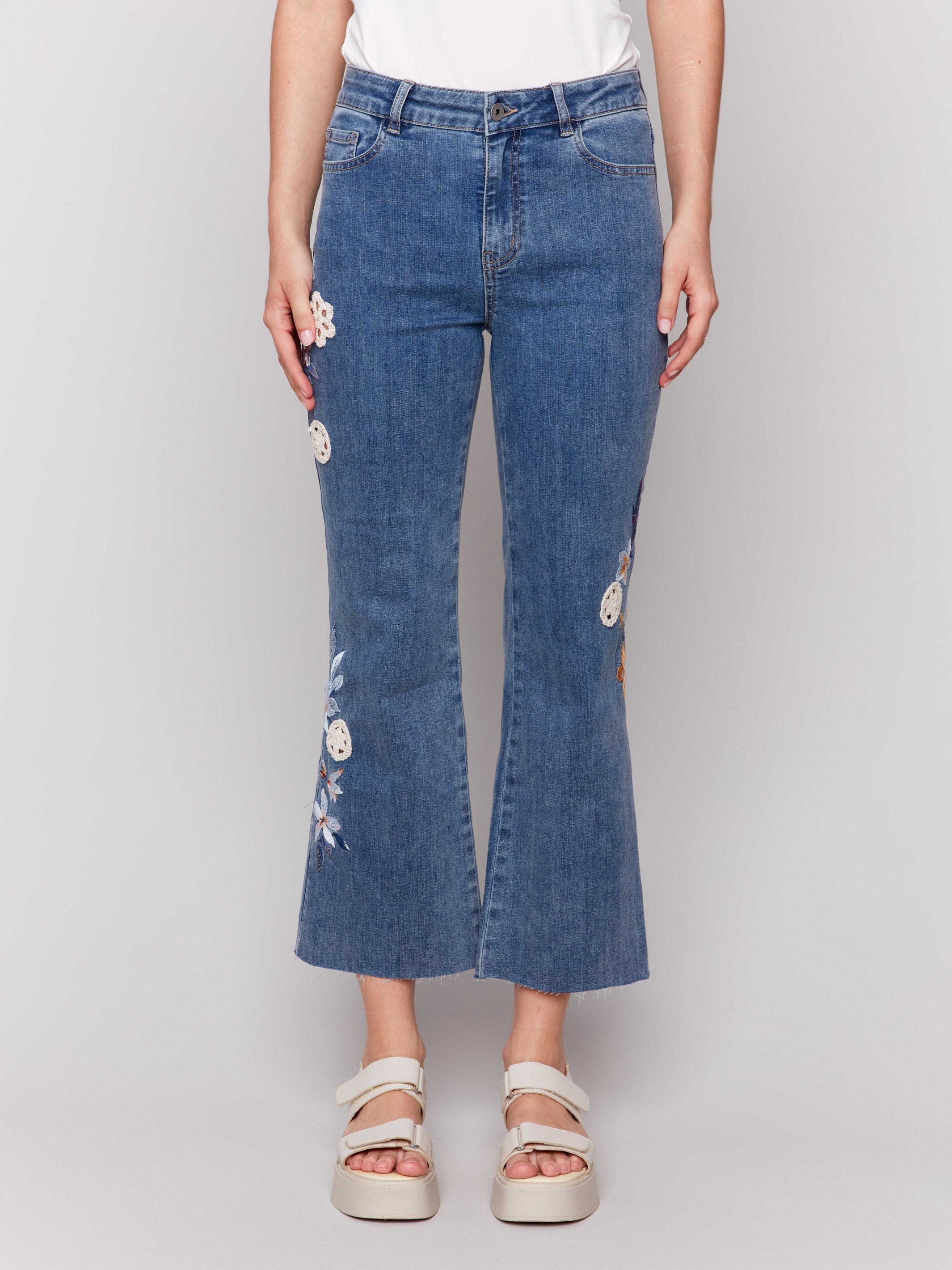 Jeans featuring floral embroidery and crochet accents in medium blue by Charlie B.