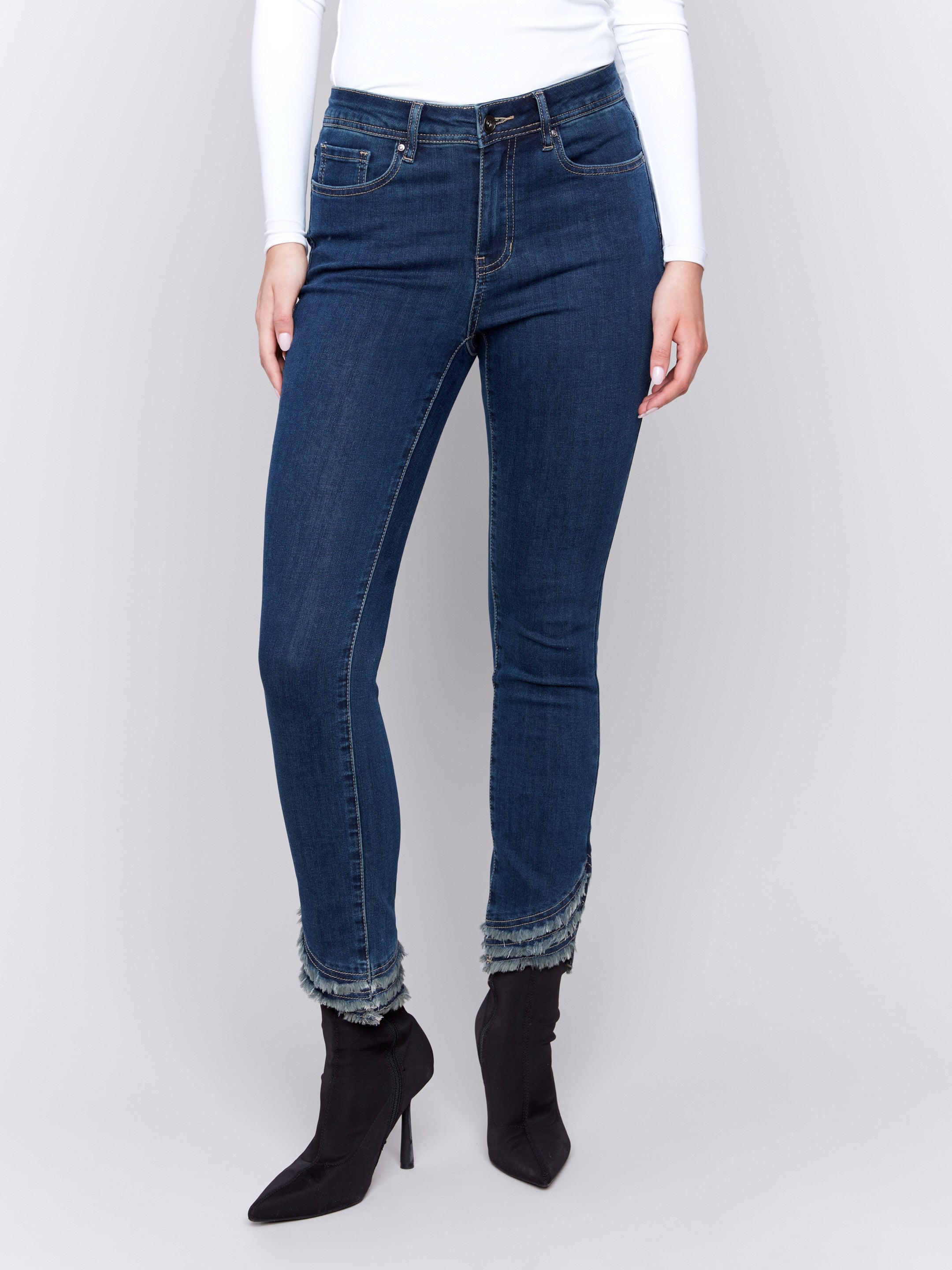 Dark blue slim-fit jeans with a mid-rise waist and frayed hem, featuring a five-pocket style by Charlie B.