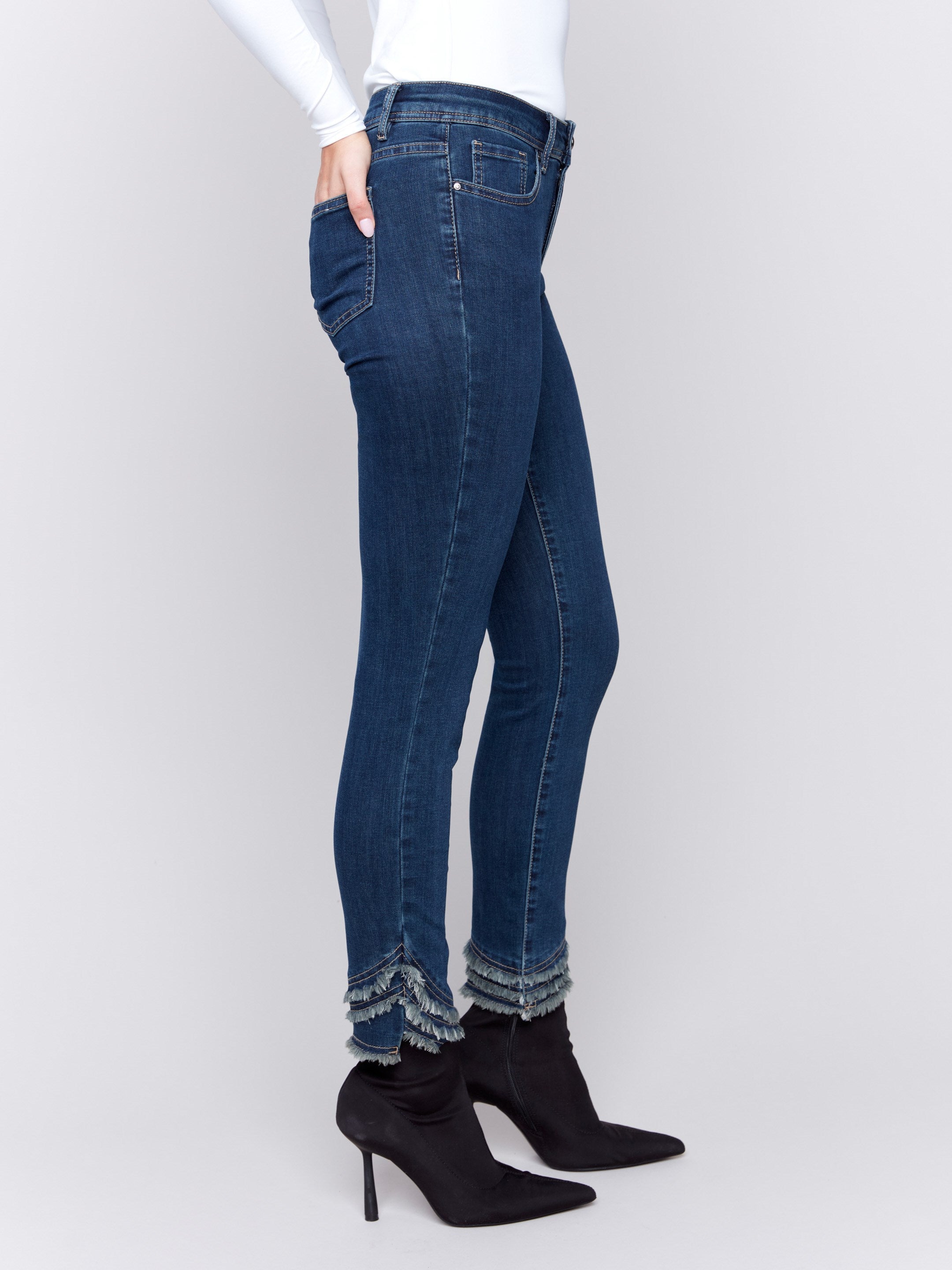 Dark blue slim-fit jeans with a mid-rise waist and frayed hem, featuring a five-pocket style by Charlie B.