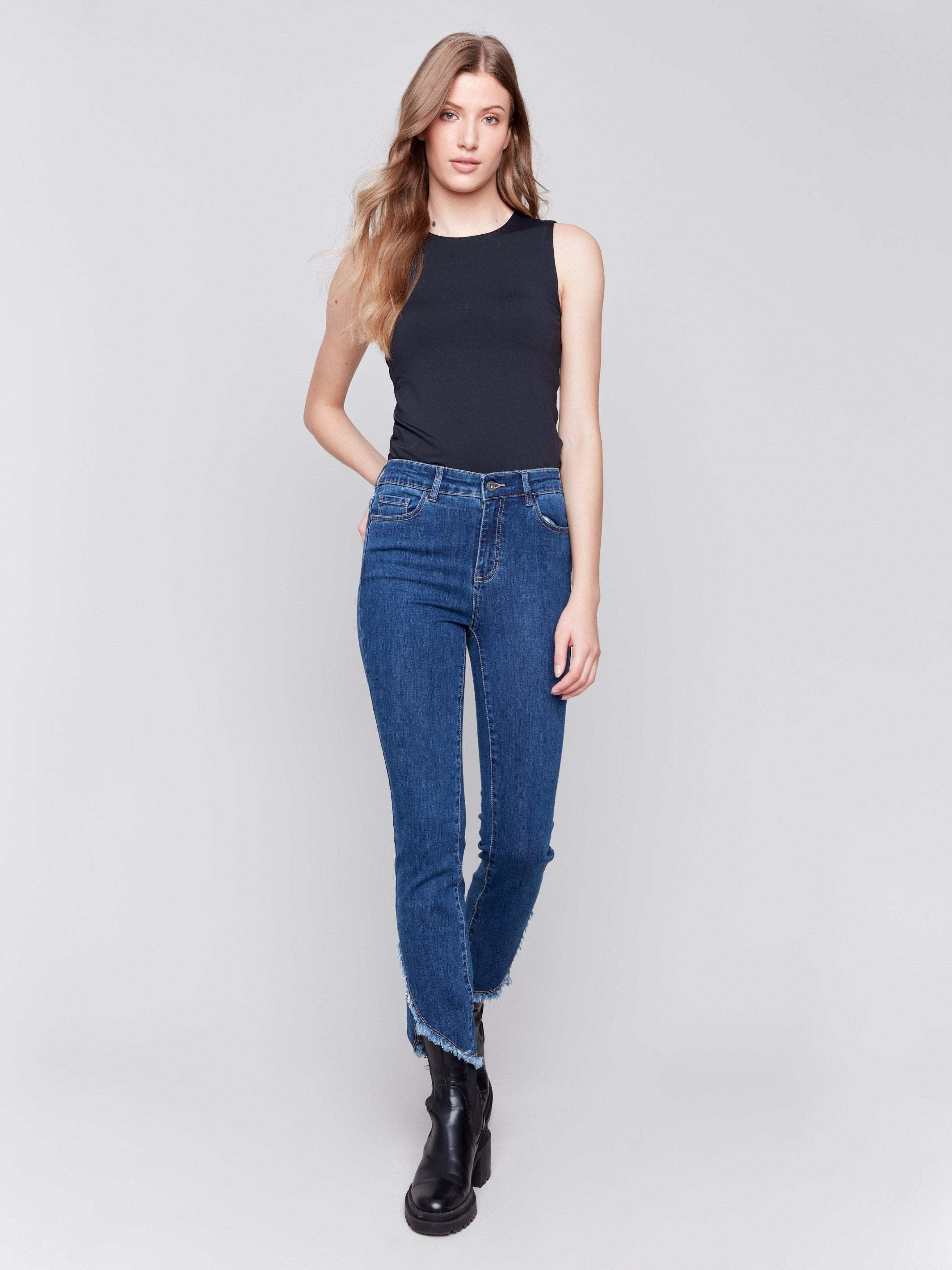 Indigo blue denim jeans with a tulip hem and bootcut design by Charlie B. Featuring a mid-rise and frayed hem details.