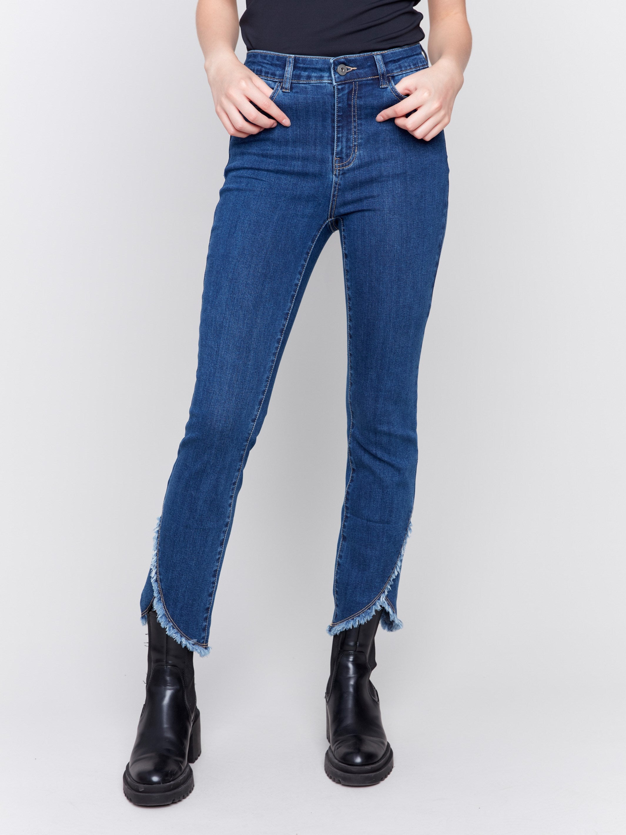 Indigo blue denim jeans with a tulip hem and bootcut design by Charlie B. Featuring a mid-rise and frayed hem details.