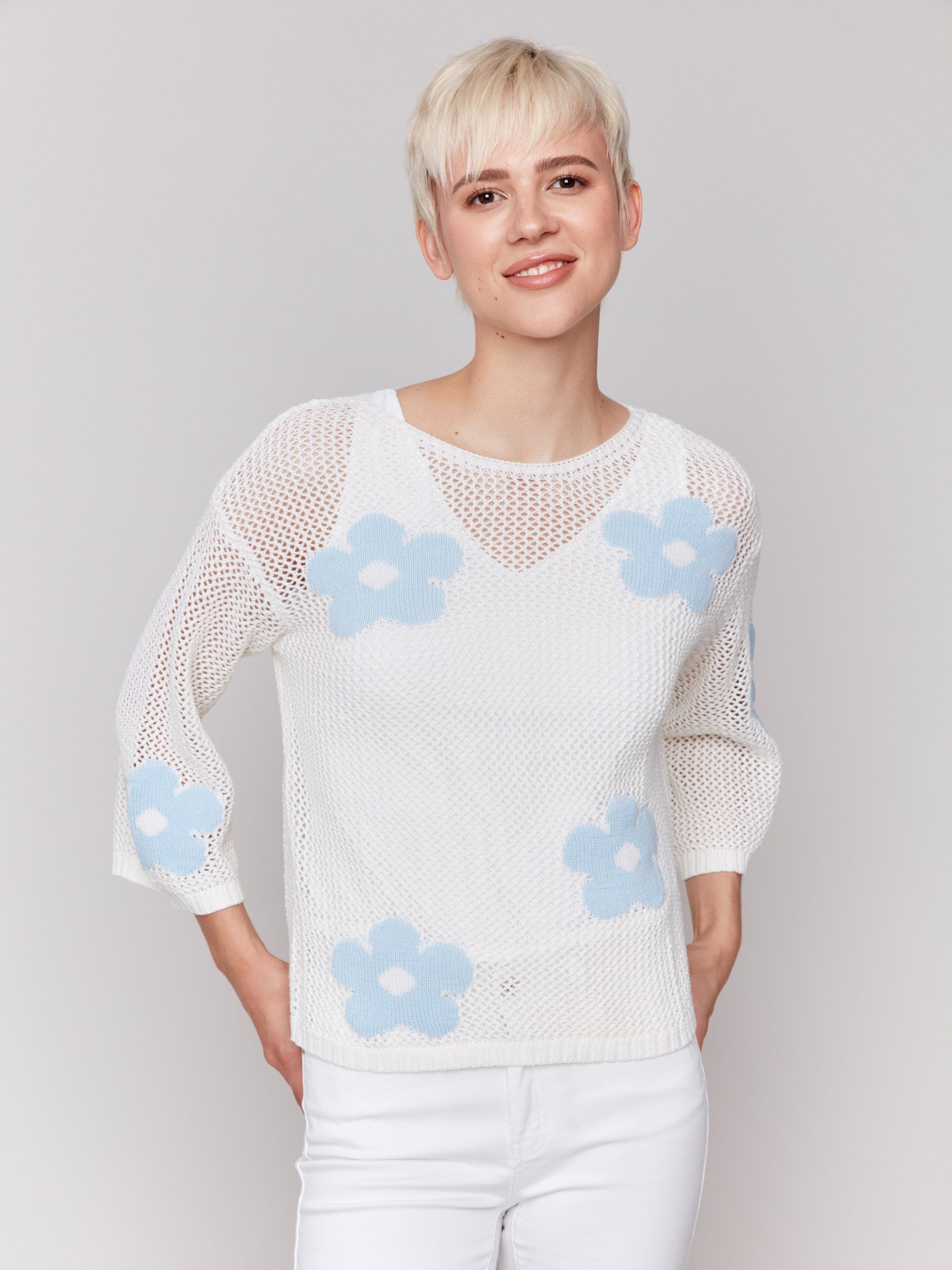 White crochet sweater with a round neckline and floral design by Charlie B.