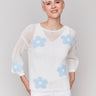 White crochet sweater with a round neckline and floral design by Charlie B.