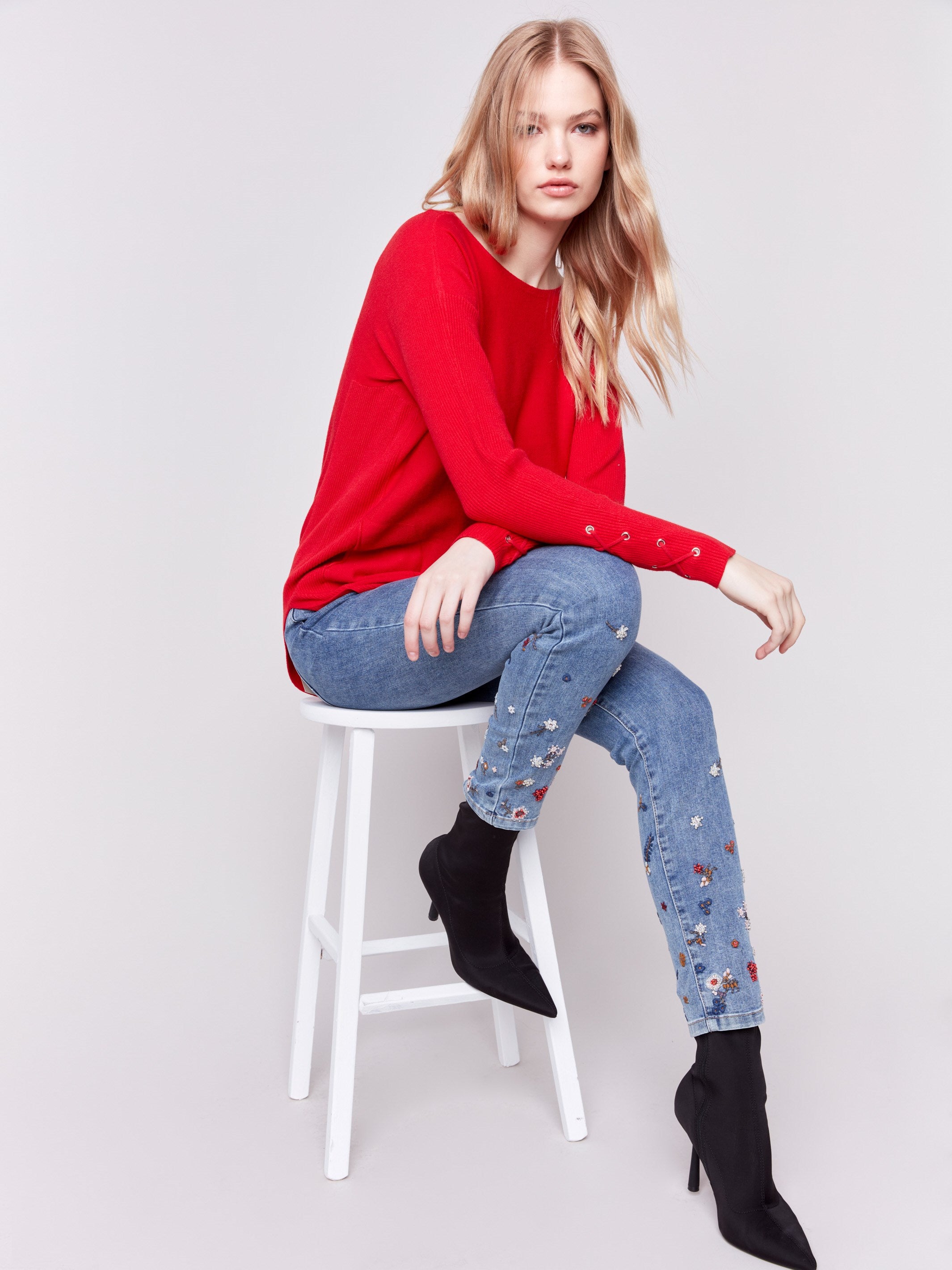 Cranberry red long-sleeved knit sweater with lace-up cuffs, rounded hem, and front pockets by Charlie B.