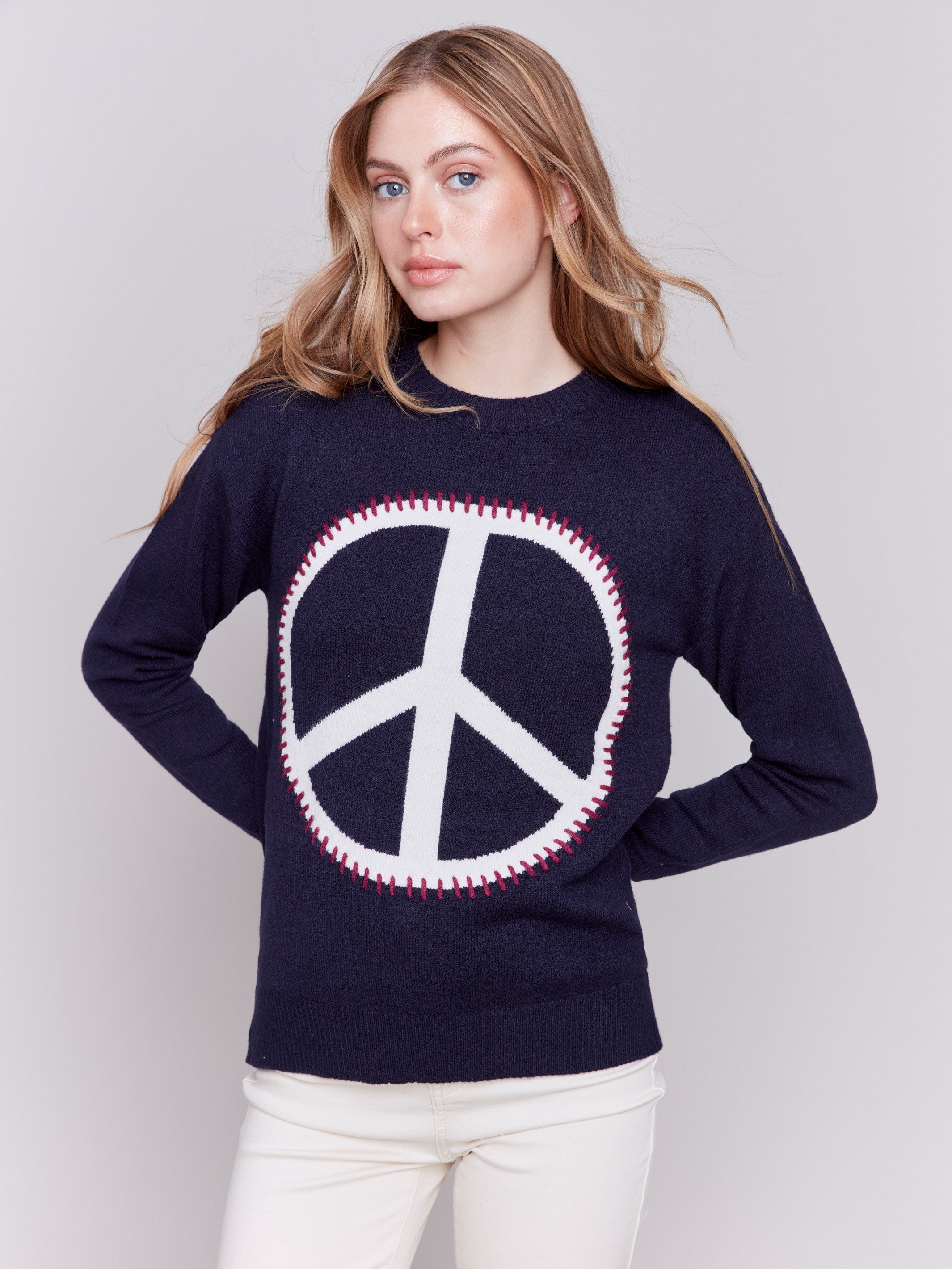 Navy blue sweater featuring a large peace sign graphic on the front with blanket stitch detailing, long sleeves, and crew neckline by Charlie B.