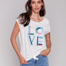 White sleeveless top with colorful 'LOVE' graphic print and a front-knot design by Charlie B.