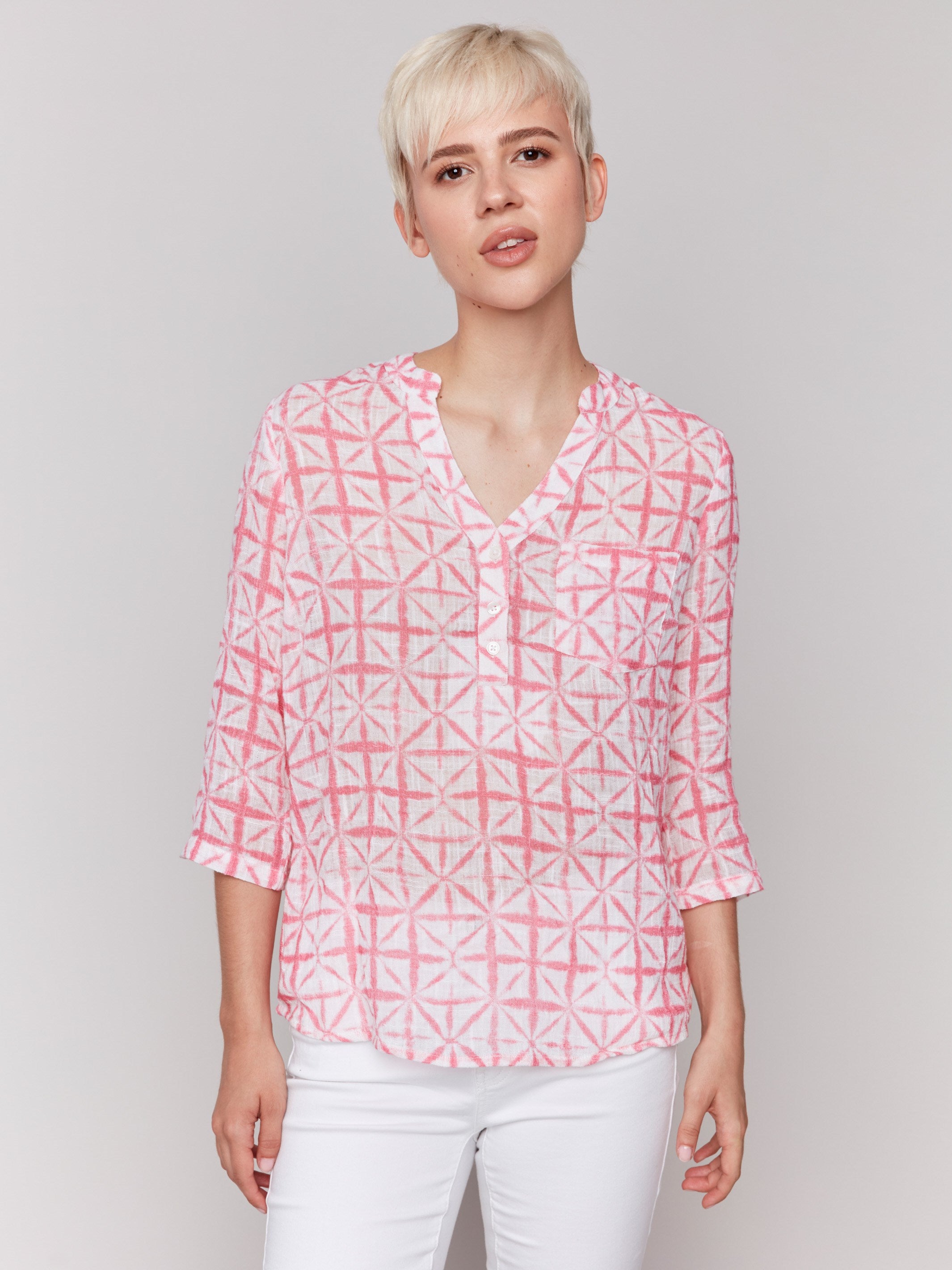 Geometric pattern blouse in begonia pink and white with a half-button front by Charlie B.