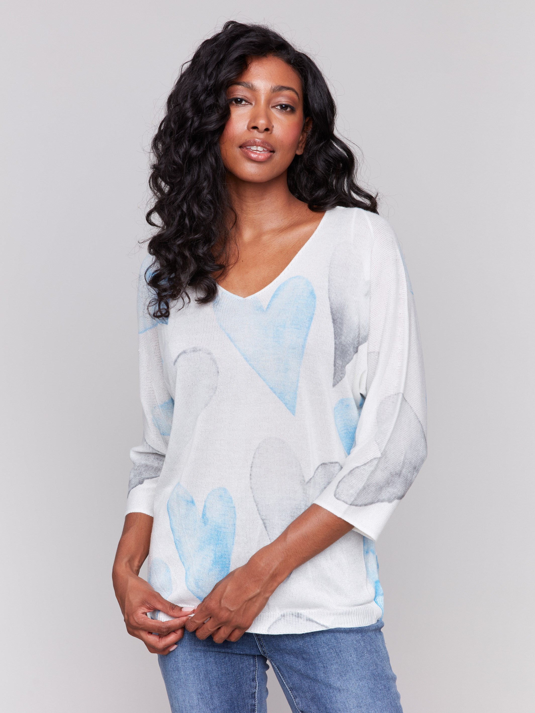 White sweater with blue heart print, featuring a v-neck and dolman sleeves by Charlie B.