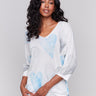 White sweater with blue heart print, featuring a v-neck and dolman sleeves by Charlie B.