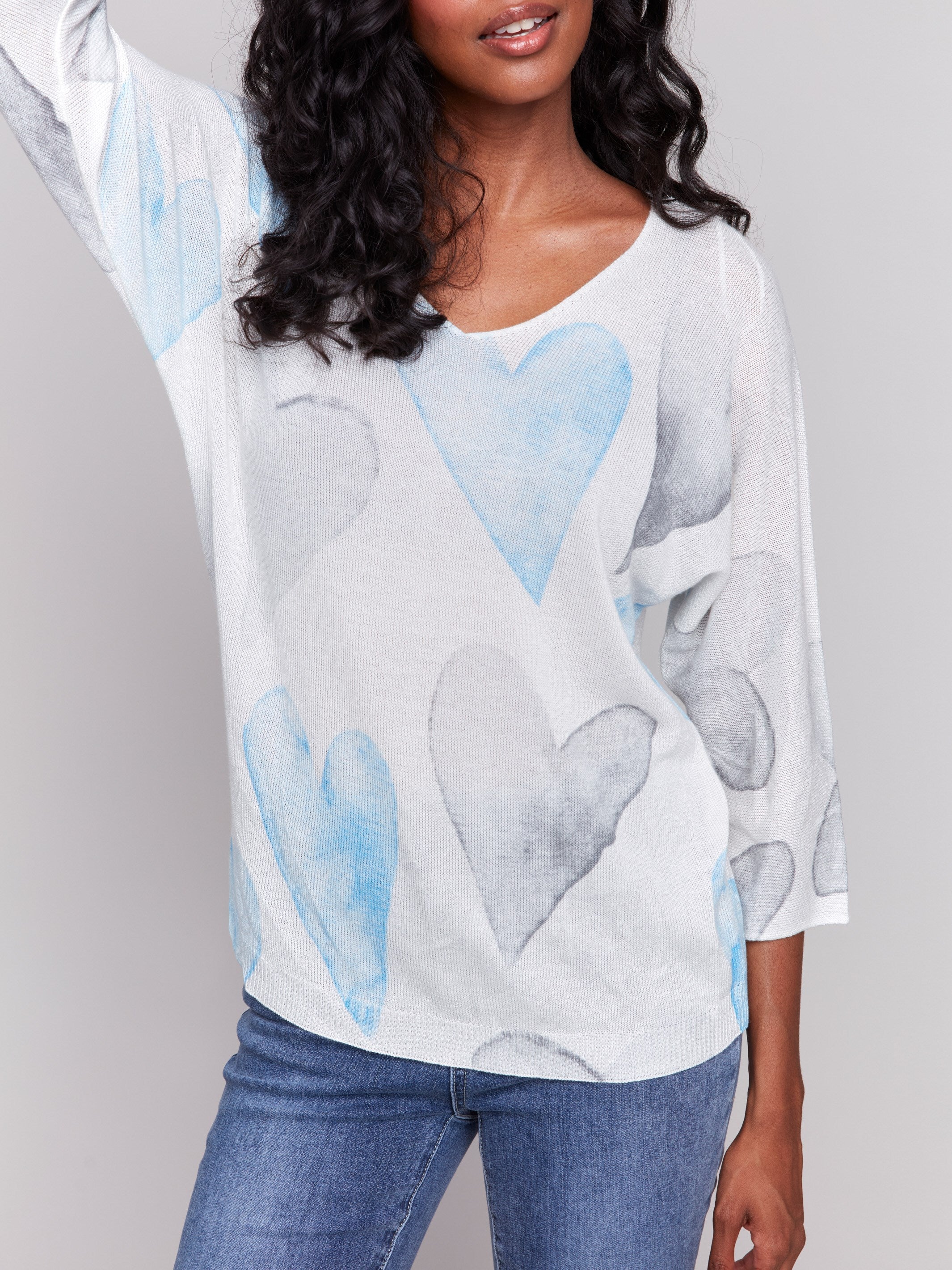 White sweater with blue heart print, featuring a v-neck and dolman sleeves by Charlie B.