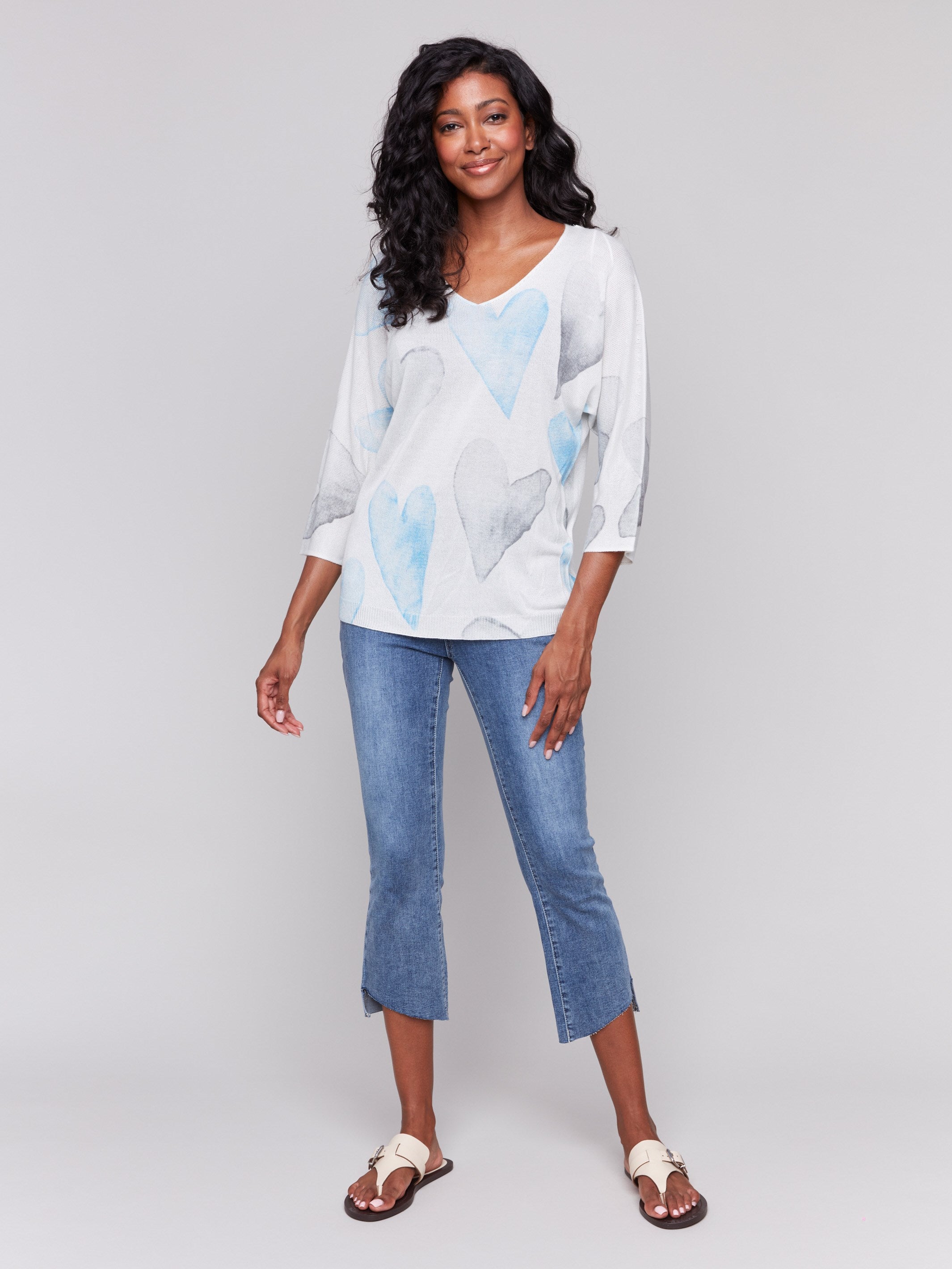 White sweater with blue heart print, featuring a v-neck and dolman sleeves by Charlie B.