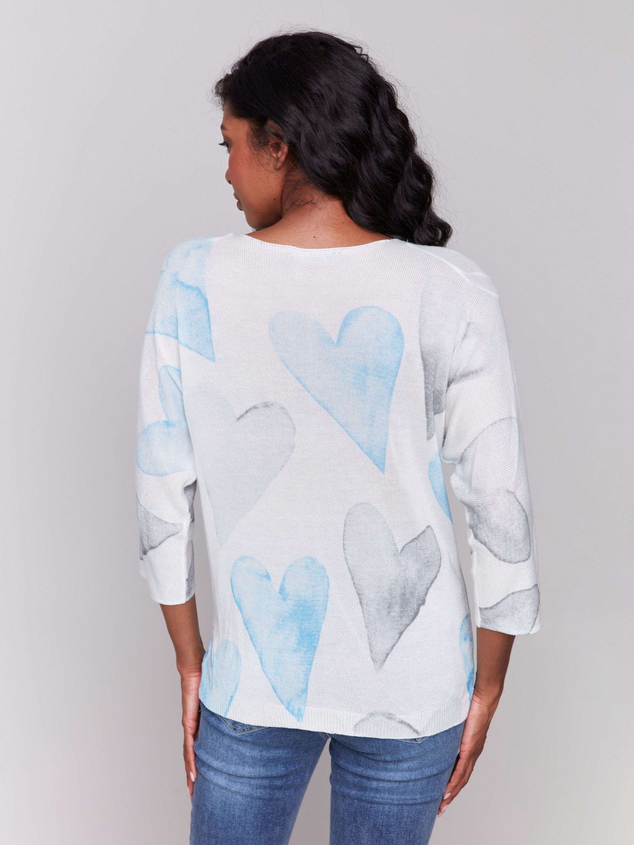 White sweater with blue heart print, featuring a v-neck and dolman sleeves by Charlie B.