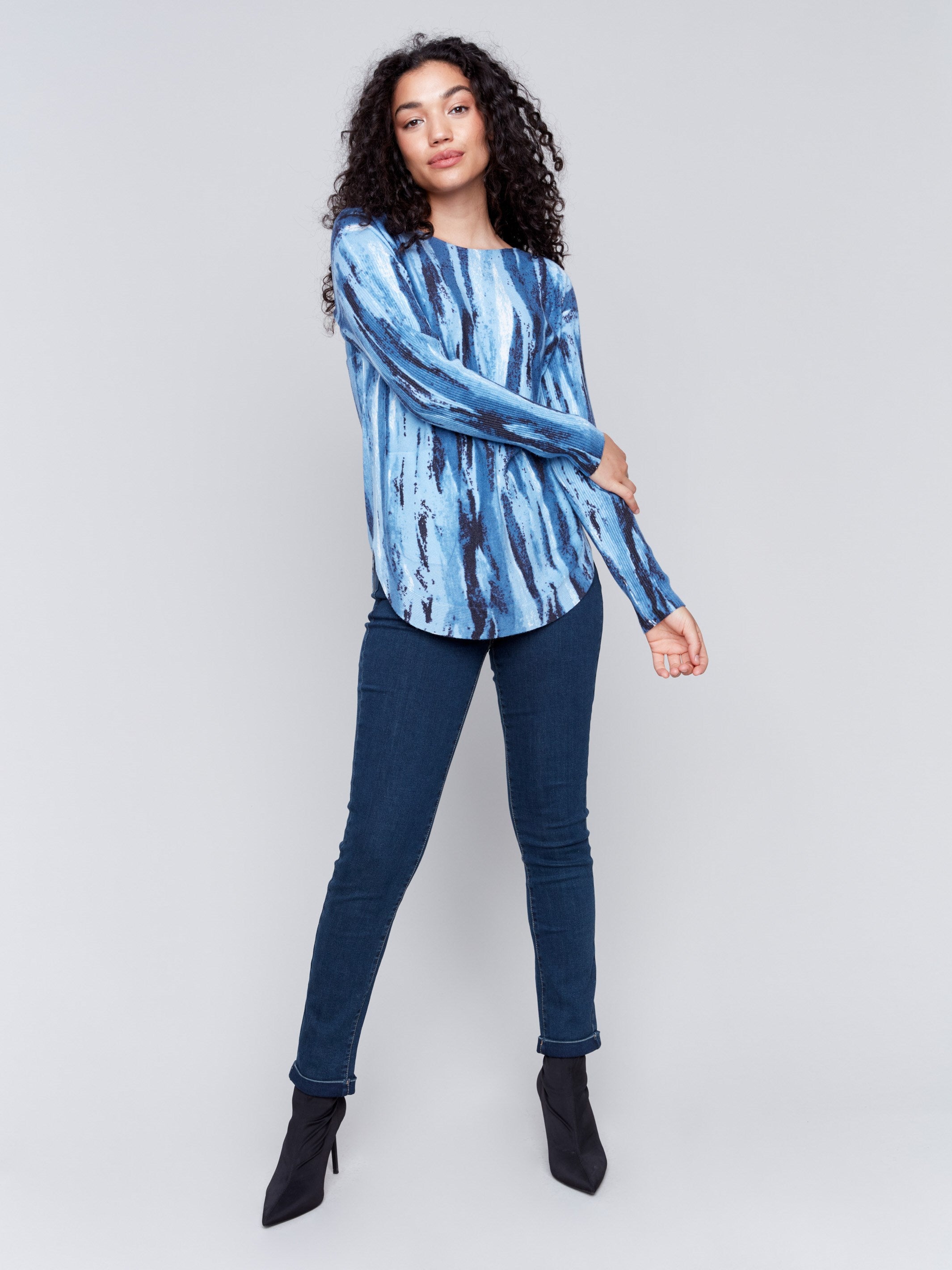 Denim-colored plush knit sweater with an abstract vertical striped pattern, round neckline, rounded hem, and side pockets by Charlie B.