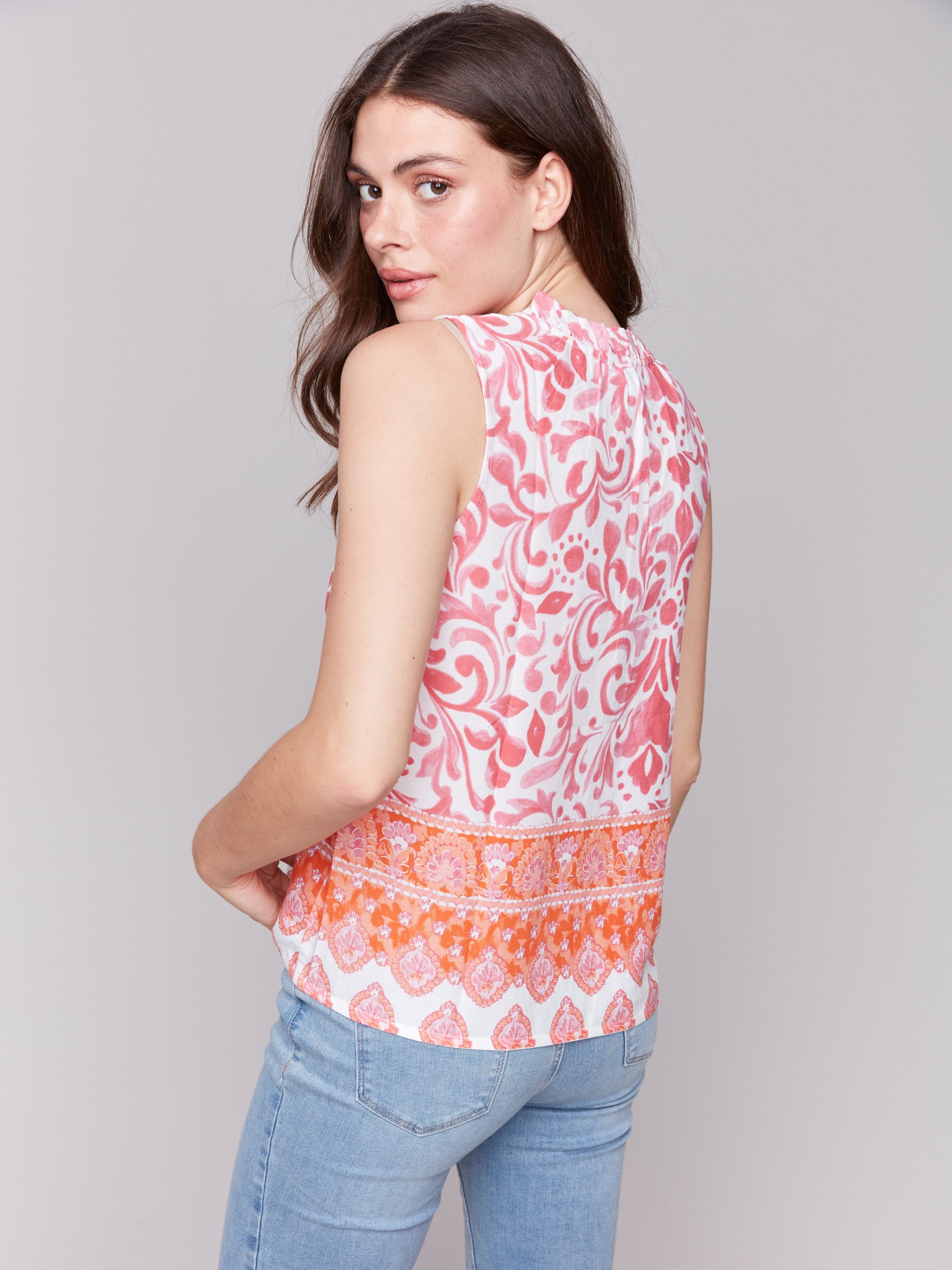 Blouse featuring a ruffle neckline in clementine and pink by Charlie B.