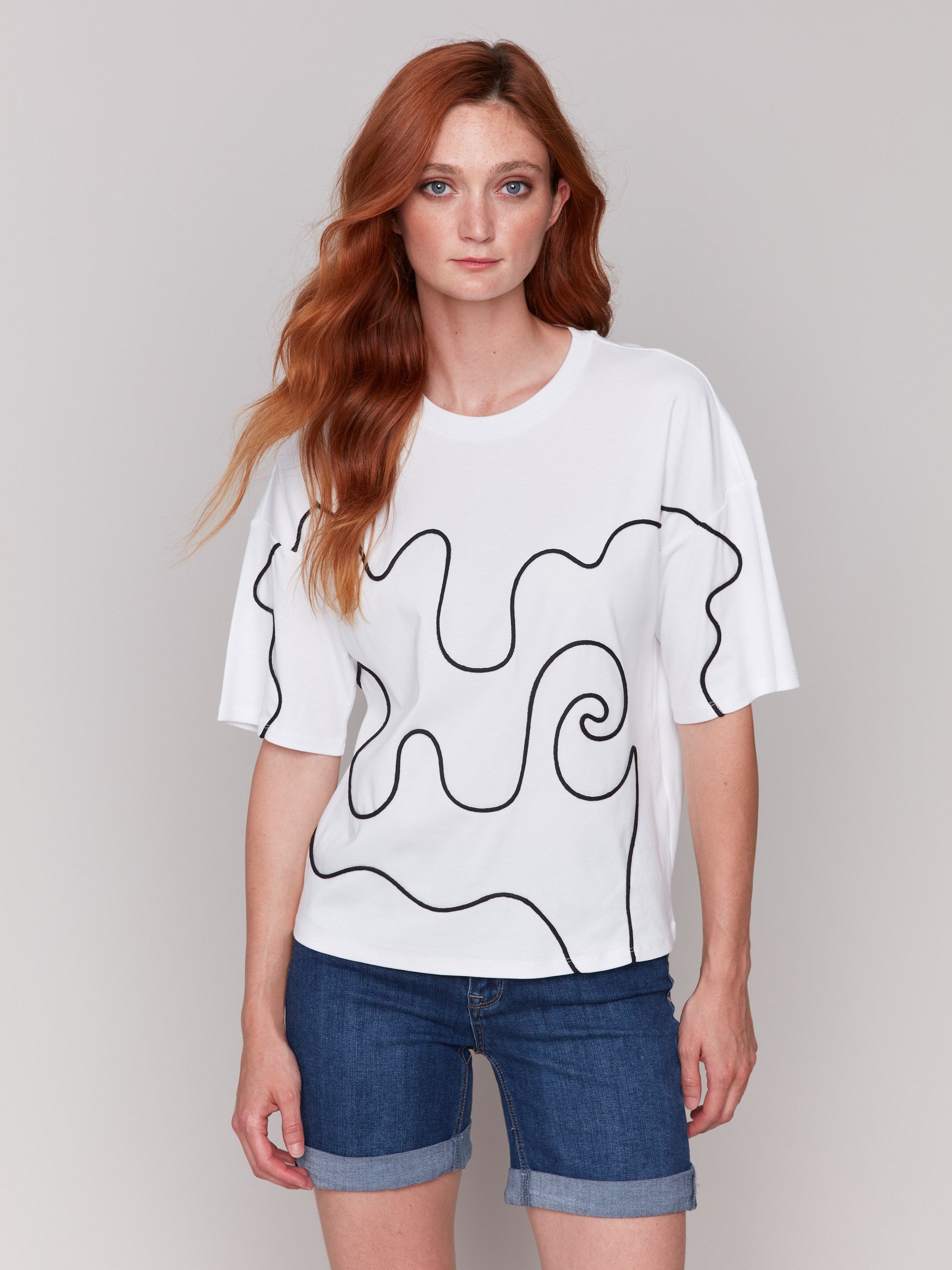 White t-shirt with drop shoulder design and black soutache accents by Charlie B.