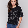 Black t-shirt with drop shoulder design, featuring white soutache detailing by Charlie B.