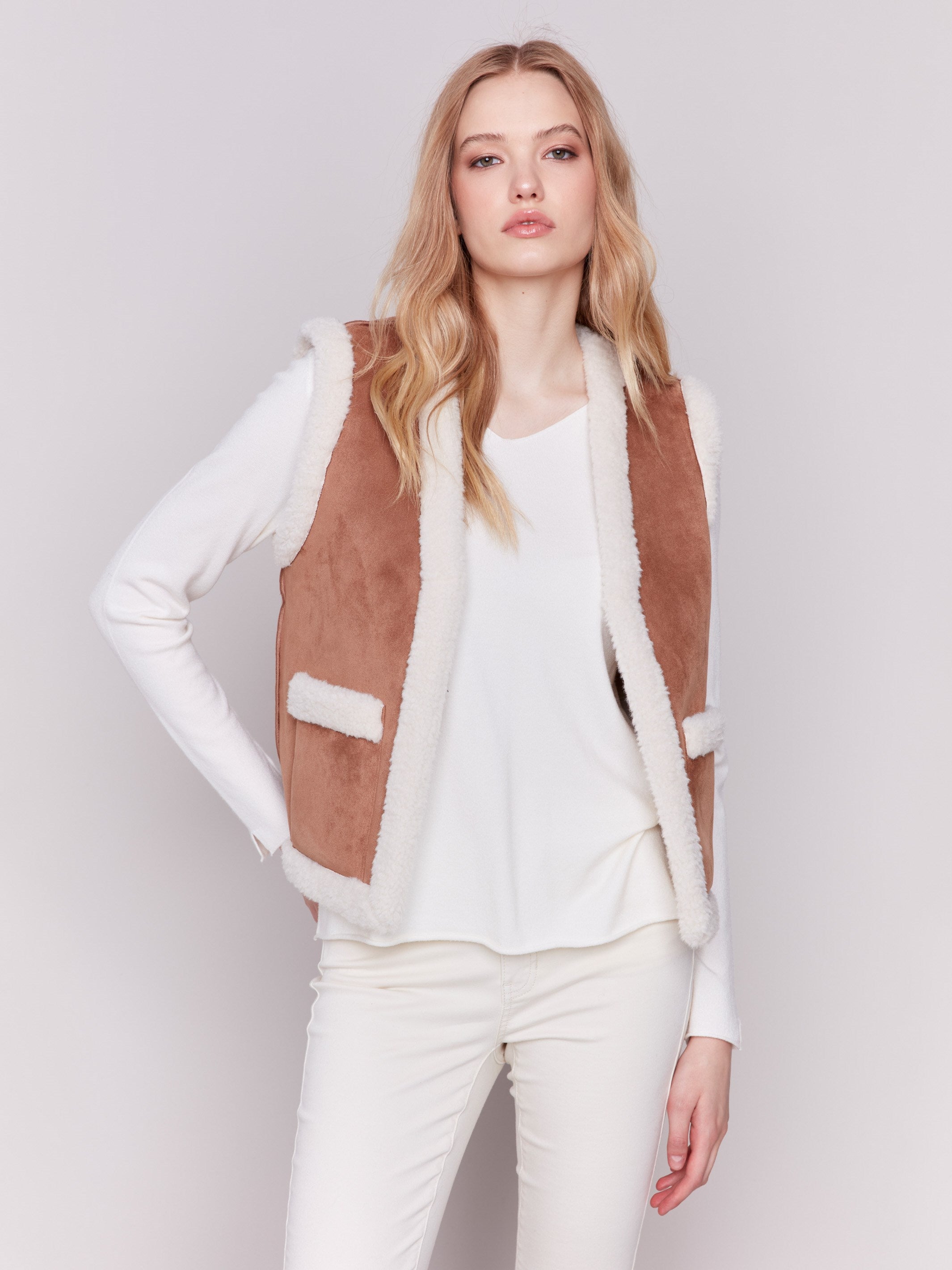 A reversible faux fur and suede vest in ecru with an open front and patch pockets by Charlie B.