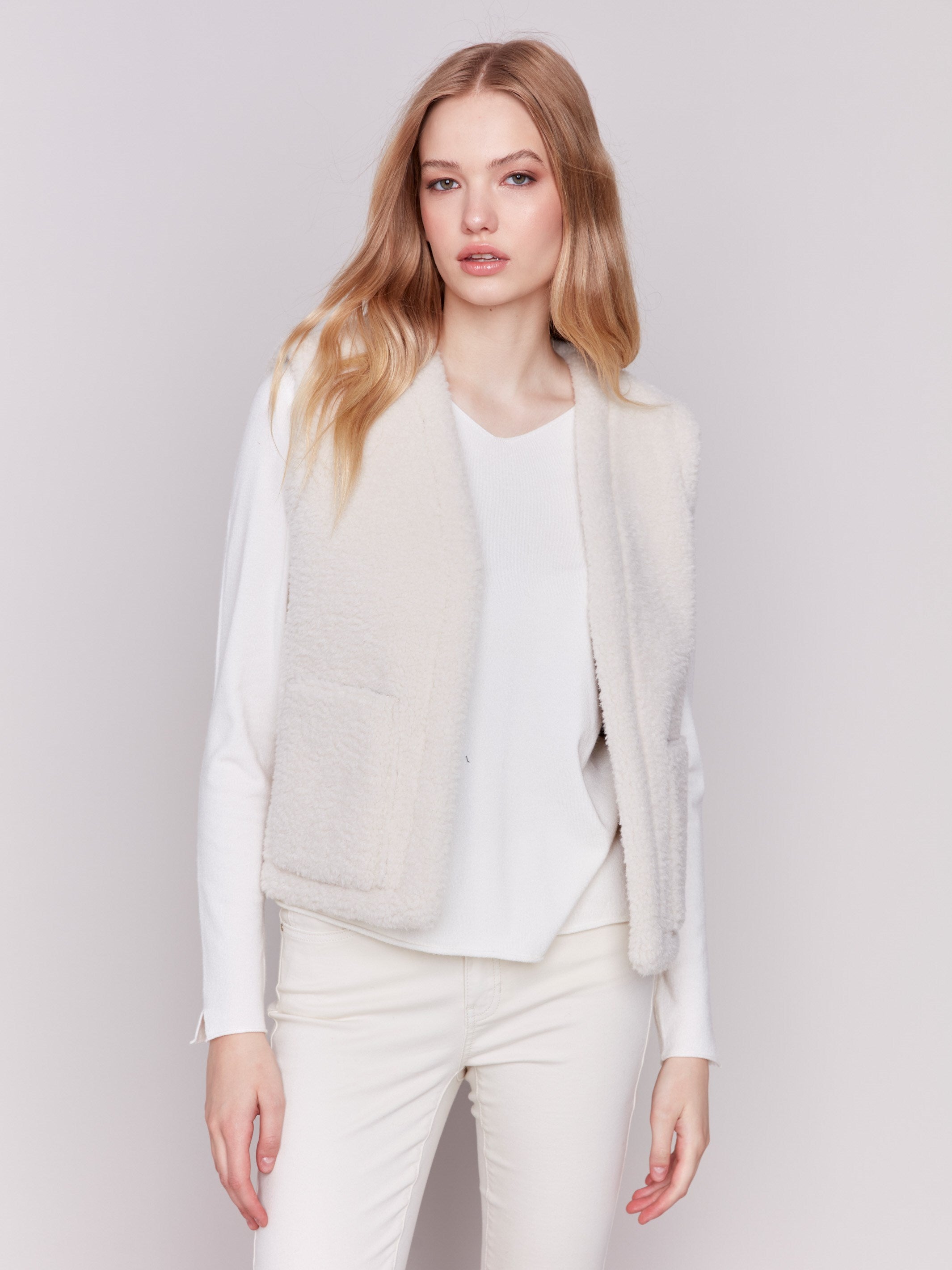 A reversible faux fur and suede vest in ecru with an open front and patch pockets by Charlie B.