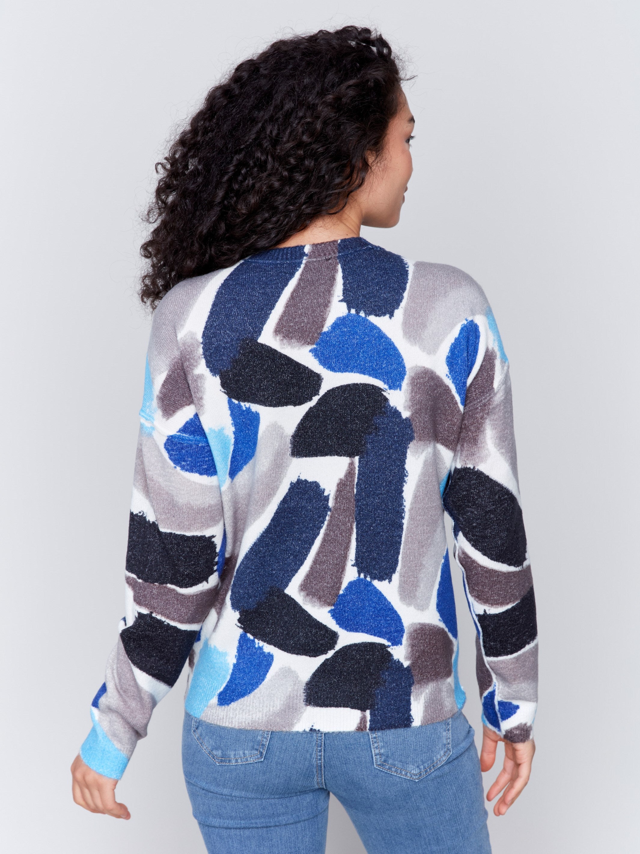 Woman wearing a reversible sweater with sapphire blue abstract prints and a crew neckline by Charlie B.