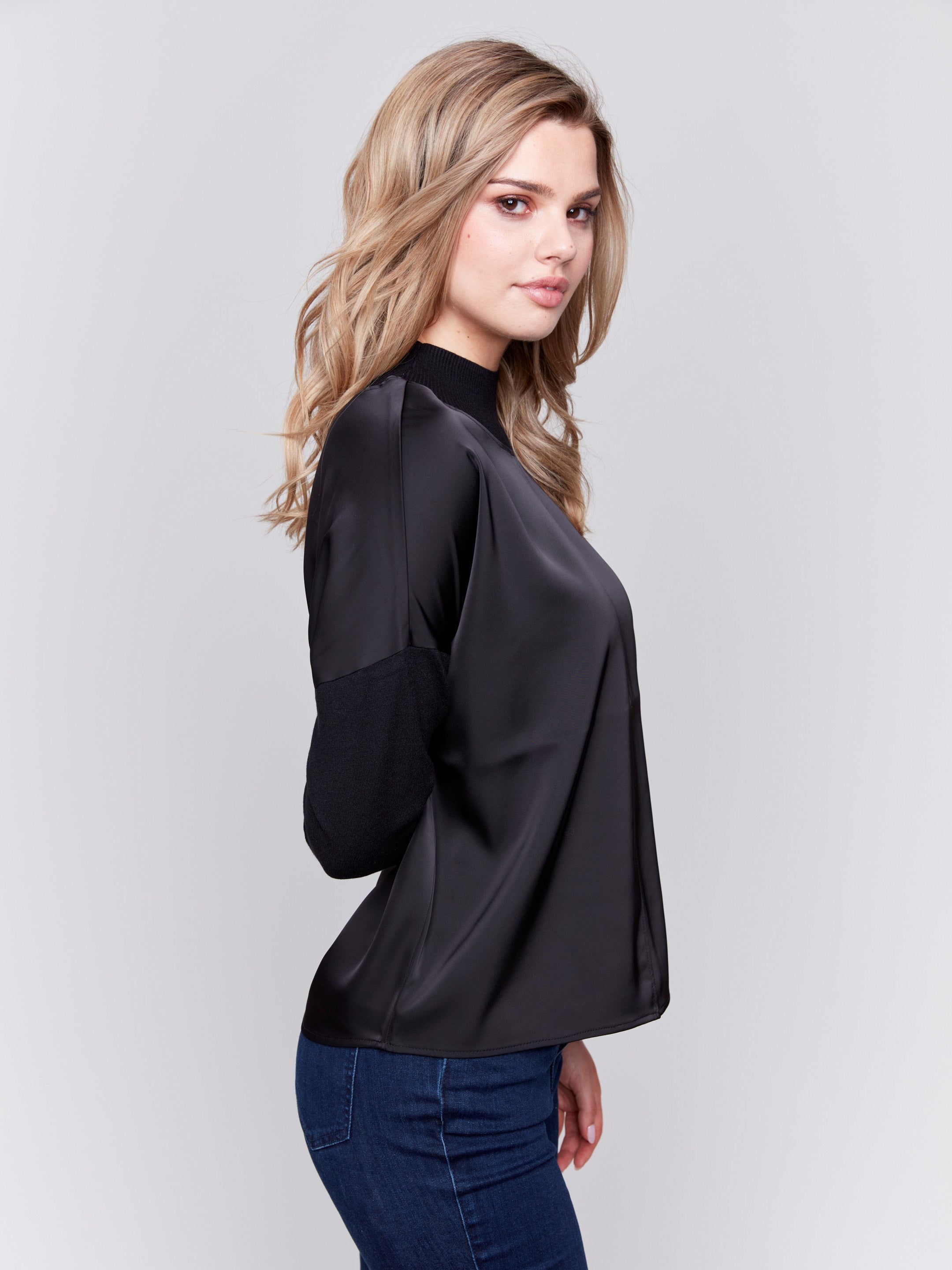 Black satin-knit top with a mock neck and front seam detail, featuring long sleeves and ribbed cuffs by Charlie B.