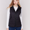 Black short quilted puffer vest with a hood, featuring a mini heart pattern and front pockets by Charlie B.