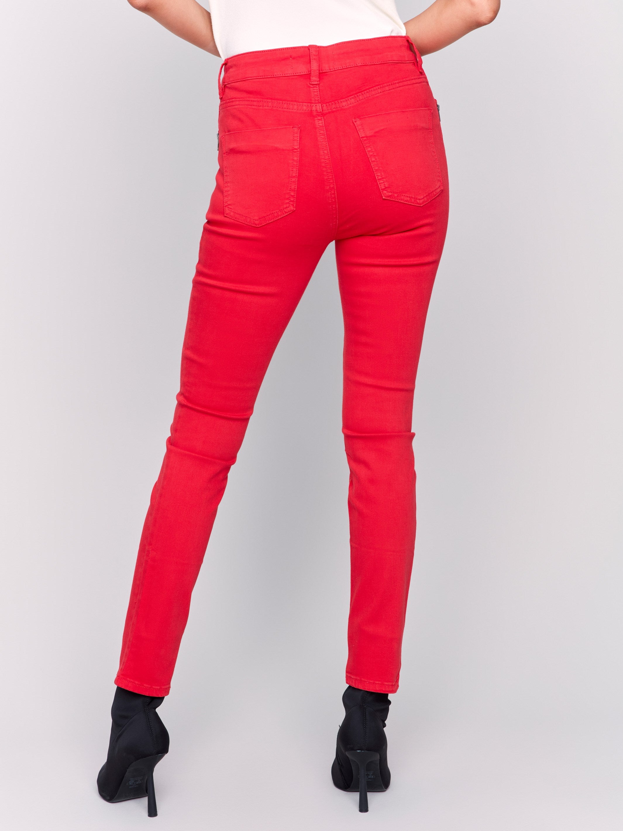 Cranberry red skinny twill pants with a mid-rise waist, skinny fit, and side zipper pocket details by Charlie B.