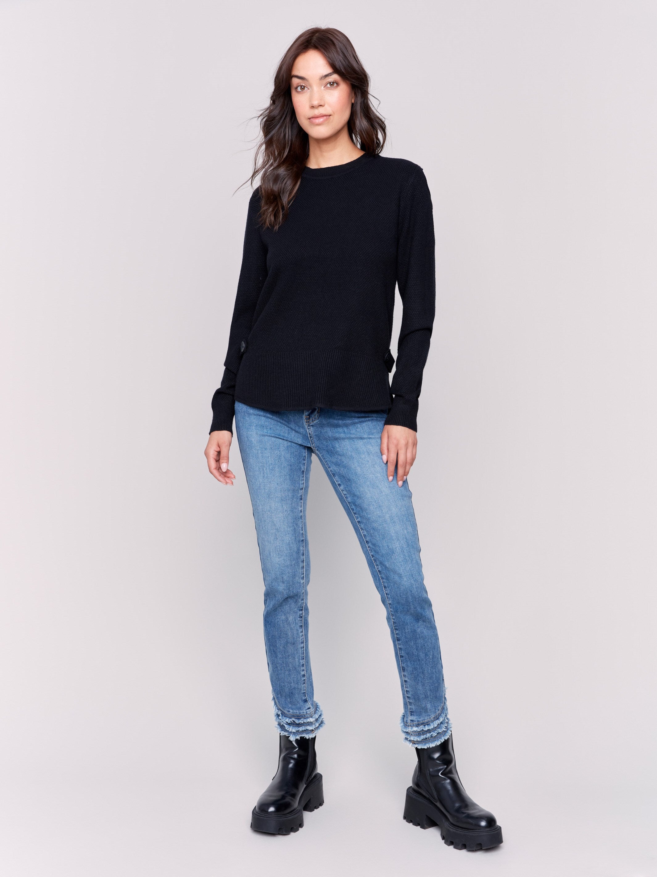 Black sweater with long sleeves featuring side tab details and a round hem by Charlie B.